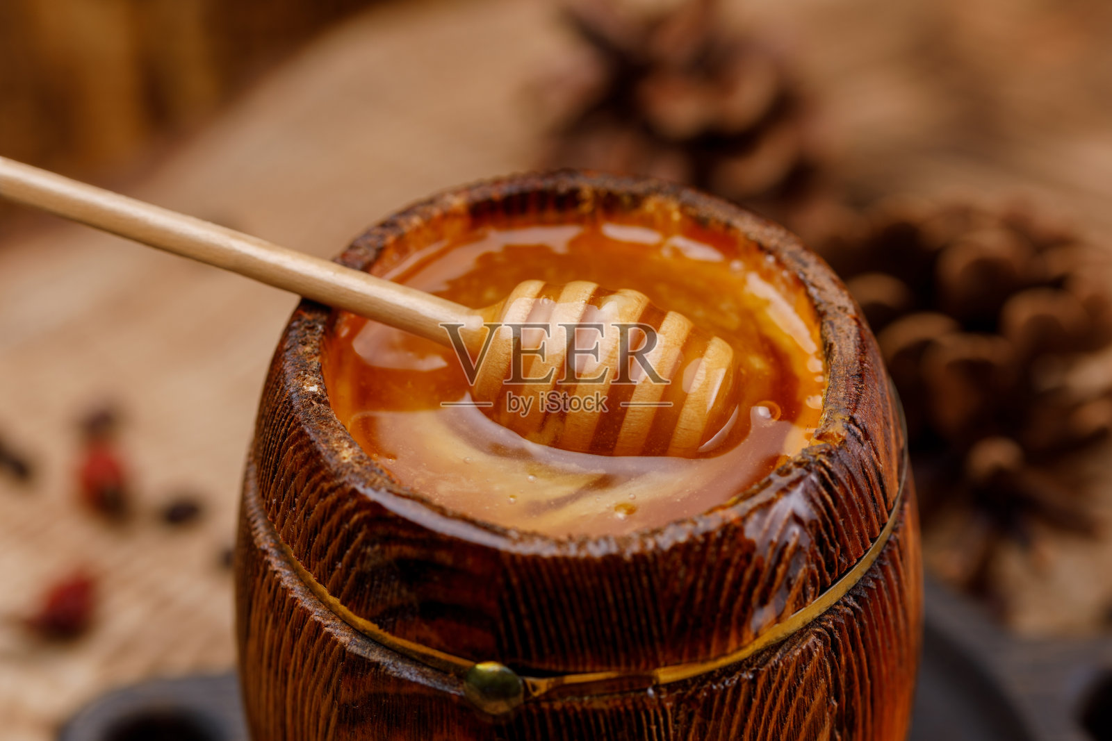 蜂蜜勺埋在一桶芬芳的新鲜蜂蜜里。照片摄影图片