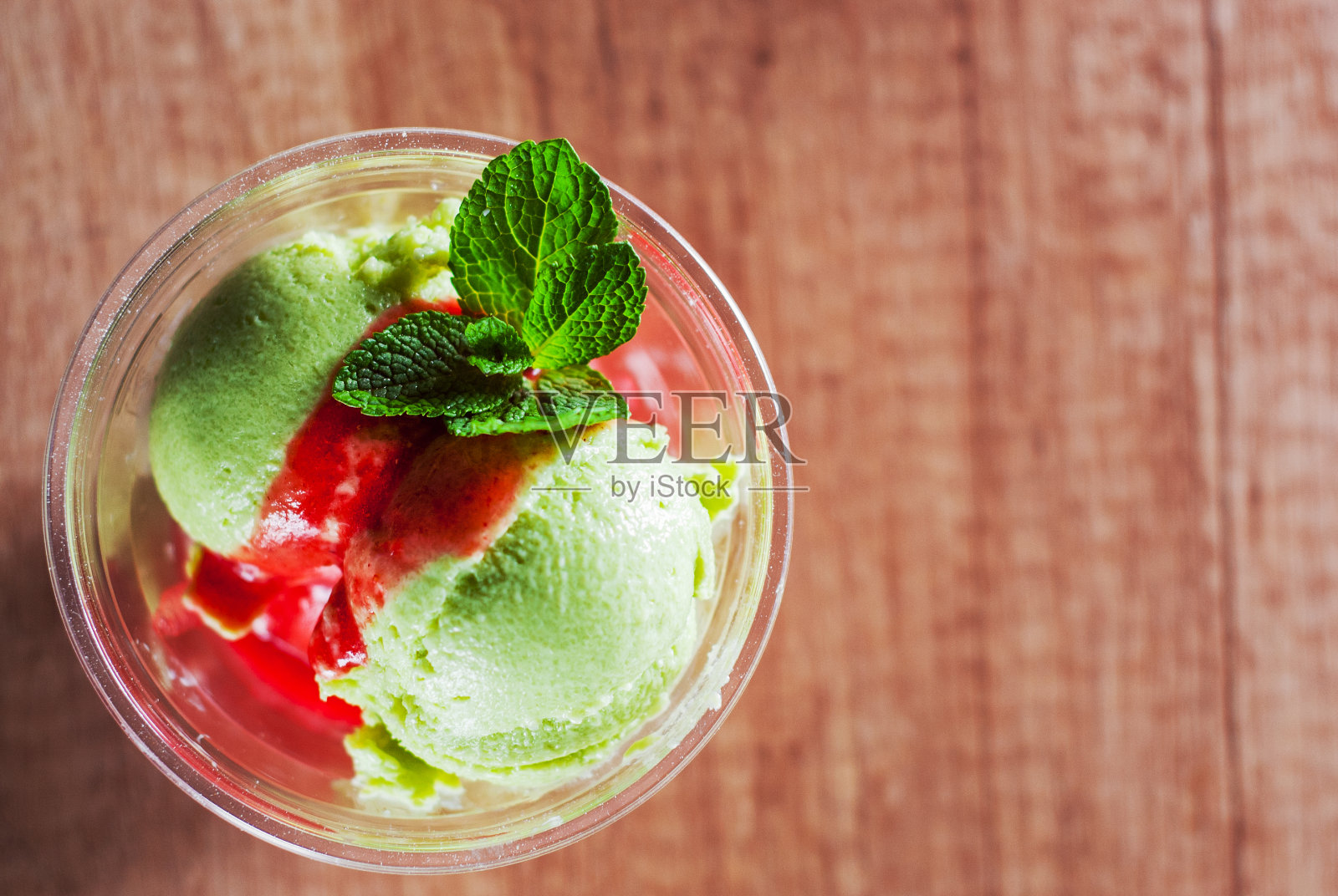 绿色有机牛油果冰淇淋和草莓冰沙，红酒与薄荷叶塑料杯照片摄影图片