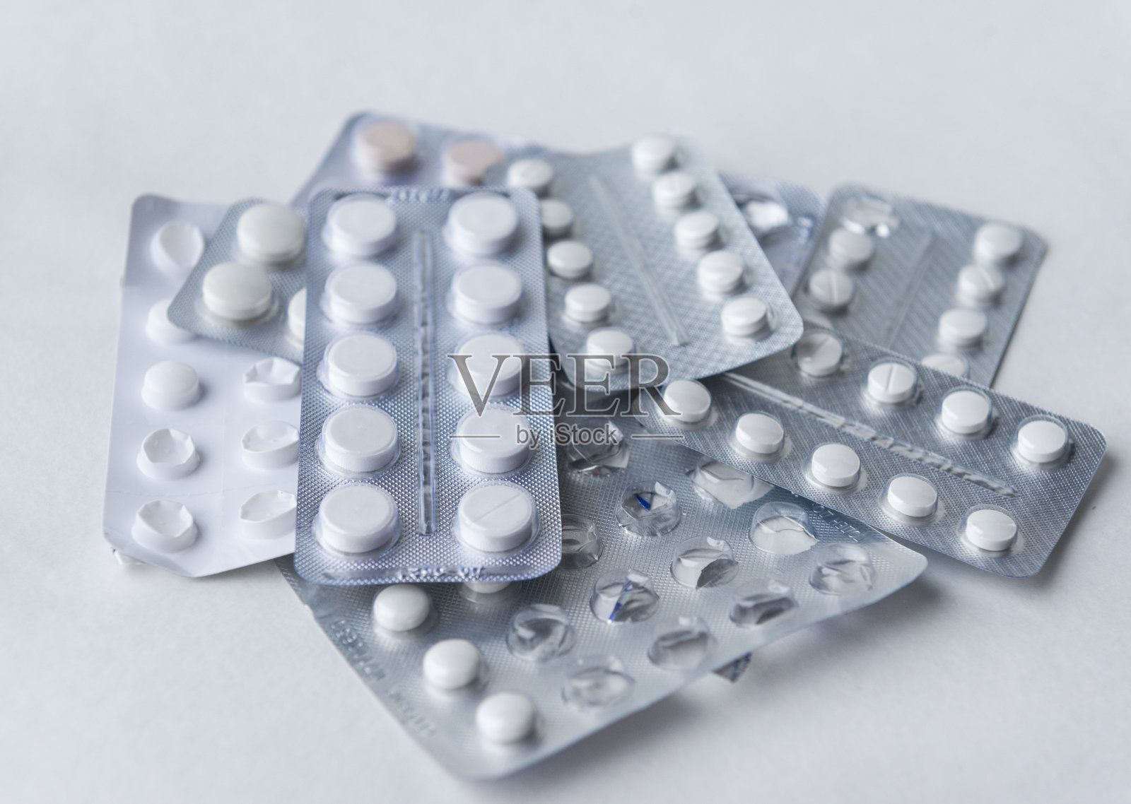 白色圆形药丸上有很多水泡，白色背景上有一包药丸照片摄影图片