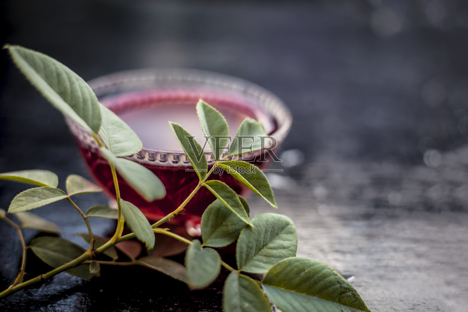 靠近印度和亚洲流行的饮料，即玫瑰柠檬水与它的全部成分，即玫瑰提取物，柠檬浓缩或柠檬精华在一个透明的瓶子和冰块。照片摄影图片