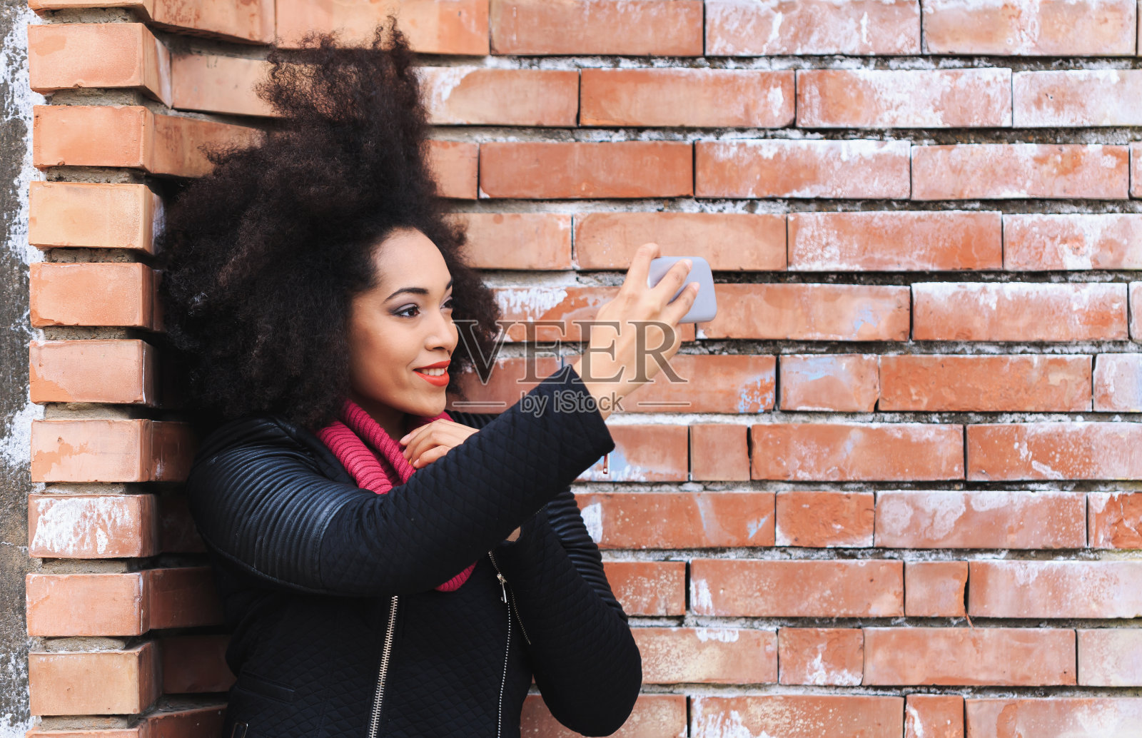一个靠在砖墙上自拍的女人照片摄影图片