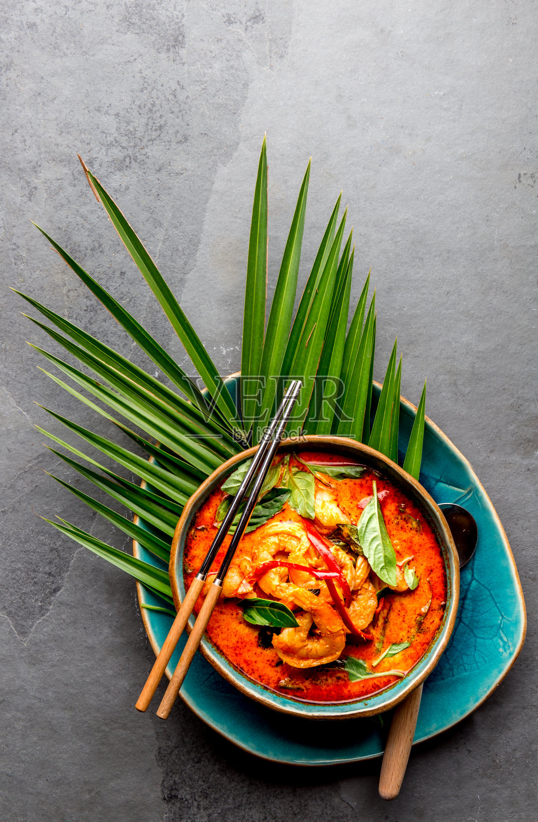 泰国虾红咖喱。泰国传统的红咖喱汤，虾，虾和椰奶。帕能咖喱在蓝色的盘子，灰色的背景照片摄影图片