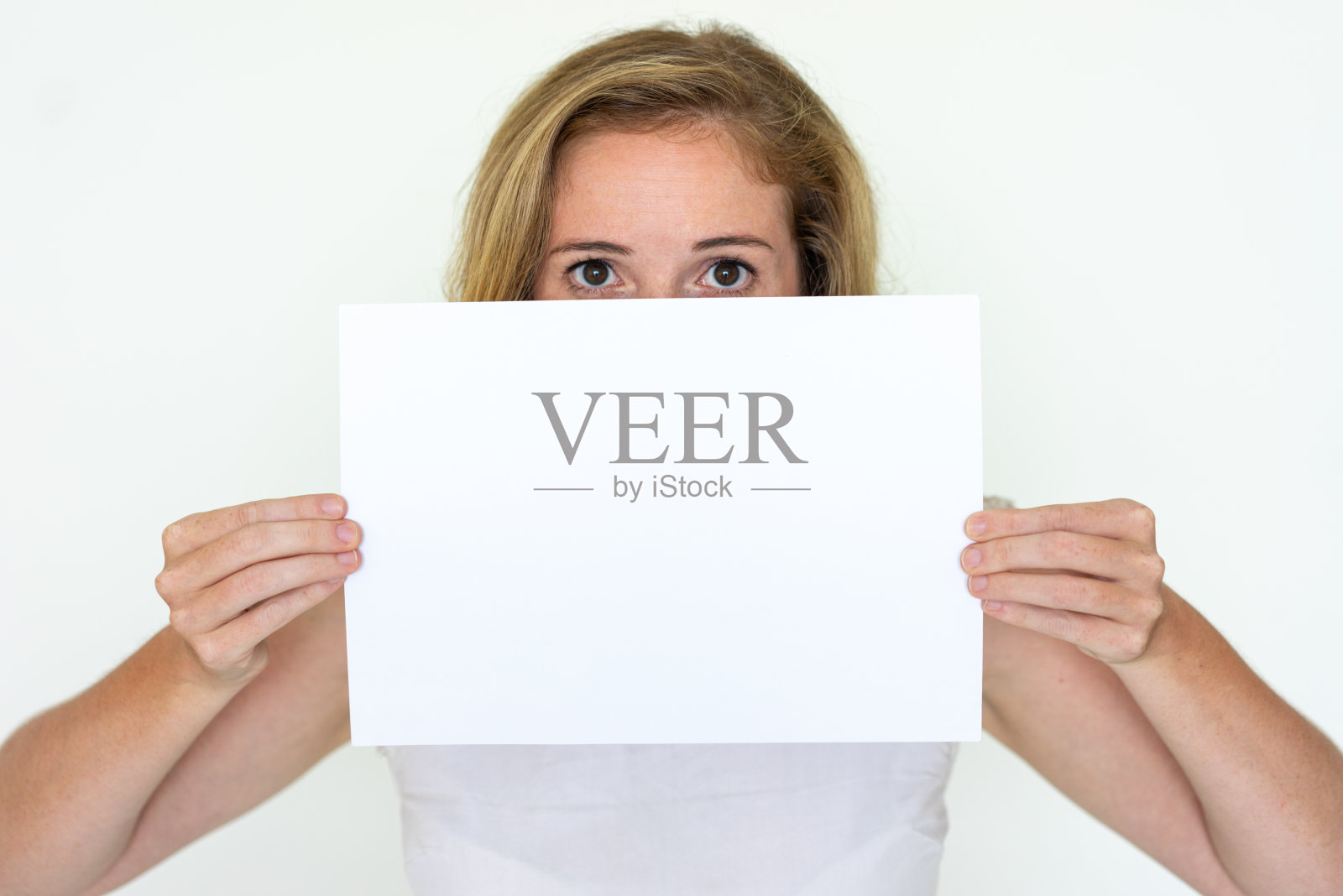 年轻女子躲在一张白纸后面照片摄影图片