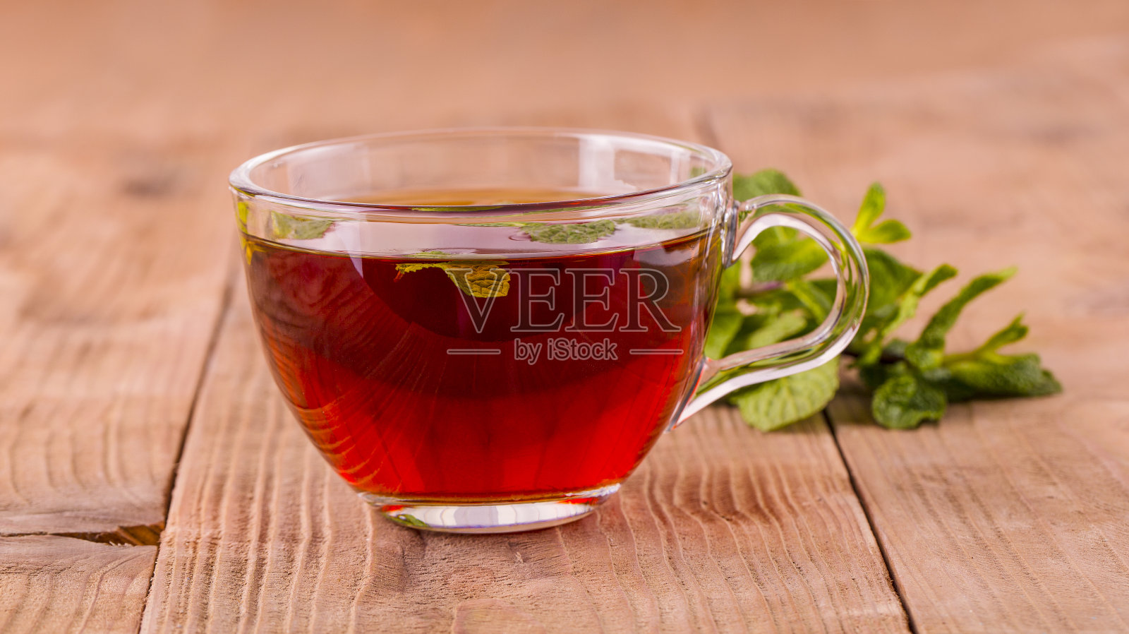 在旧的木制背景上放着薄荷的茶杯。照片摄影图片