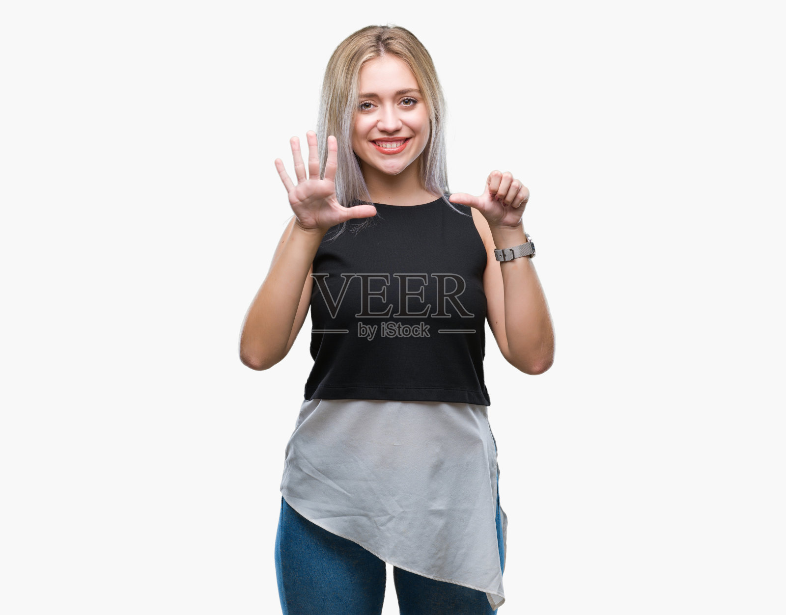 年轻的金发女子在孤立的背景显示和指着第6个手指，同时自信和快乐的微笑。照片摄影图片