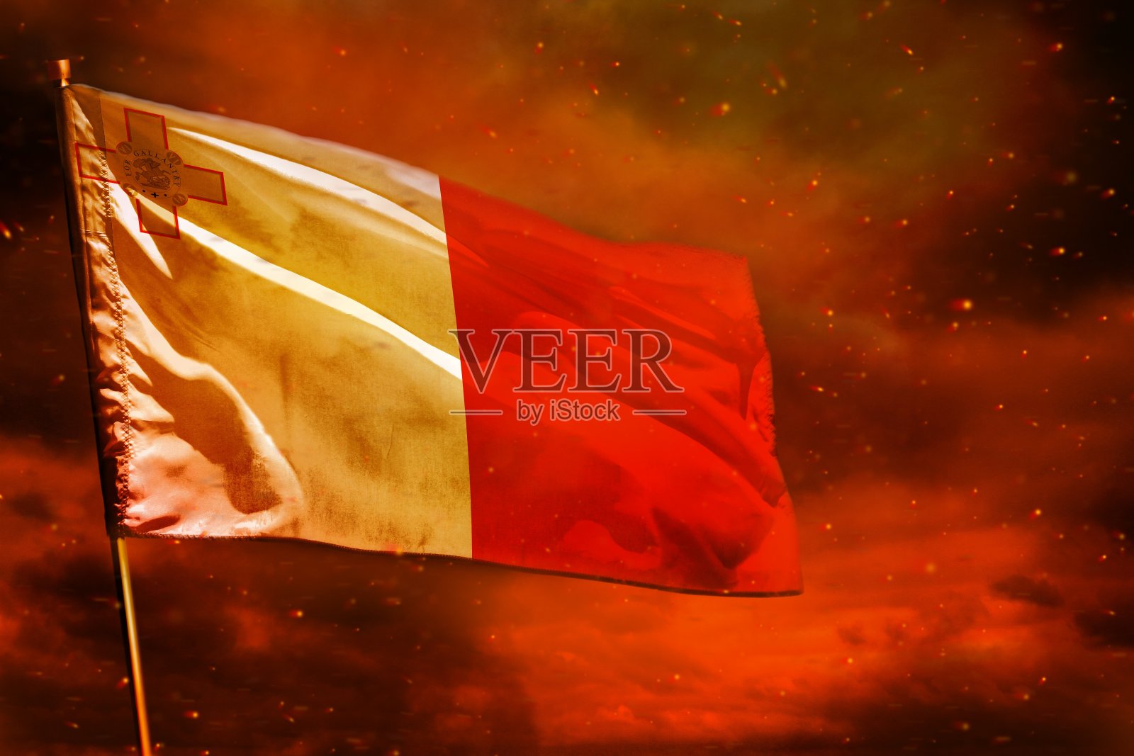 马耳他国旗在深红色的天空中飘扬，背景是烟柱。麻烦的概念。照片摄影图片