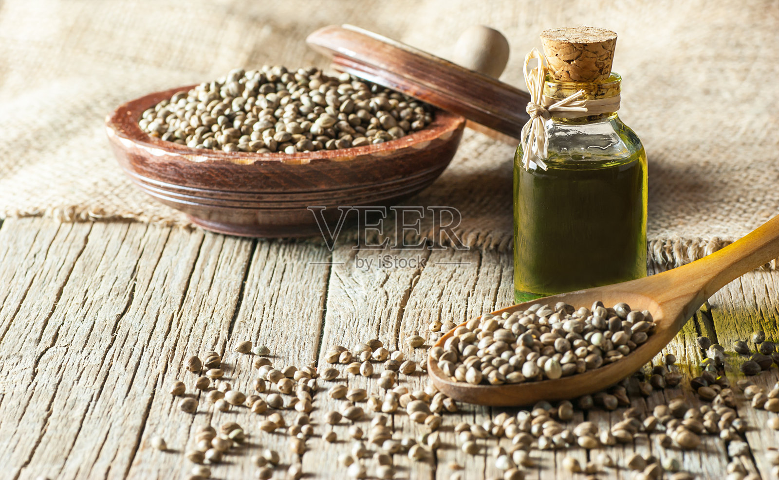 堆干的有机大麻种子或大麻植物种子勺和碗与玻璃大麻种子油在木制背景。大麻草的概念。大麻种子用鸟食代替照片摄影图片