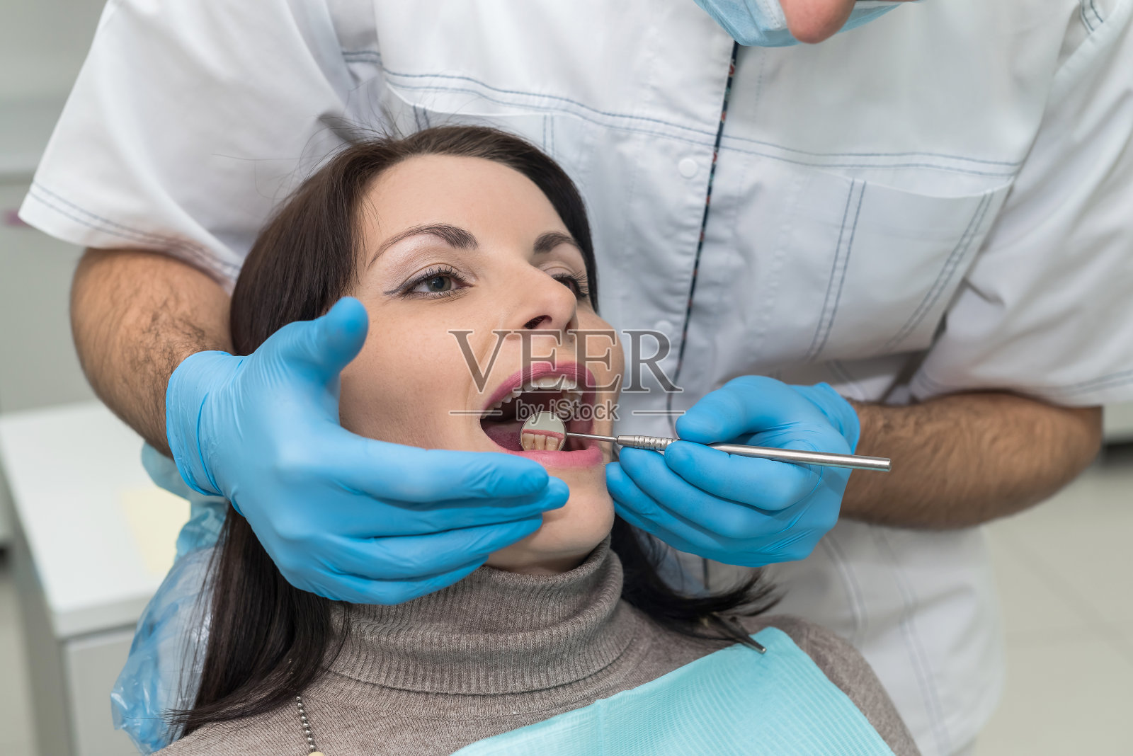 医生用镜子仔细检查病人的牙齿照片摄影图片