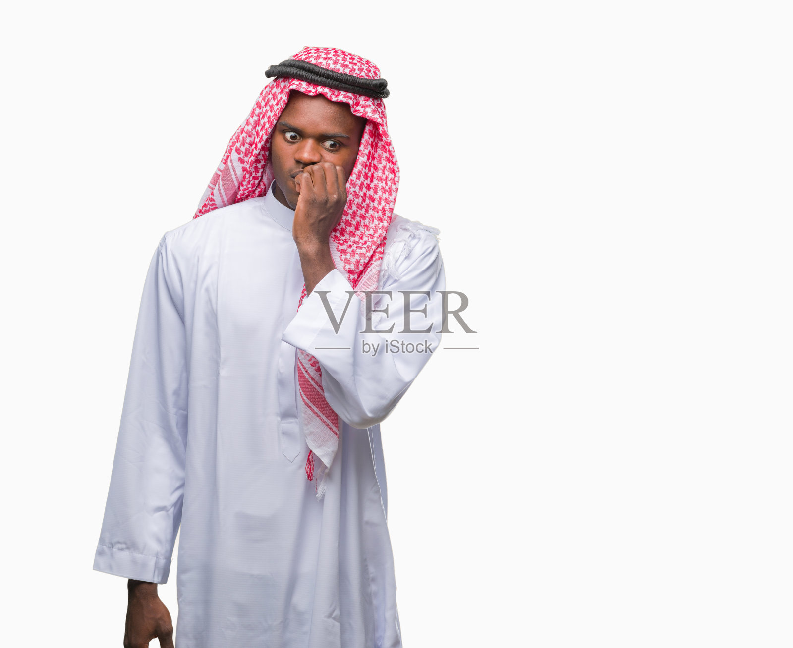 年轻的阿拉伯裔非洲人穿着传统的keffiyeh在孤立的背景下看起来紧张和紧张，手在嘴上咬指甲。焦虑的问题。照片摄影图片