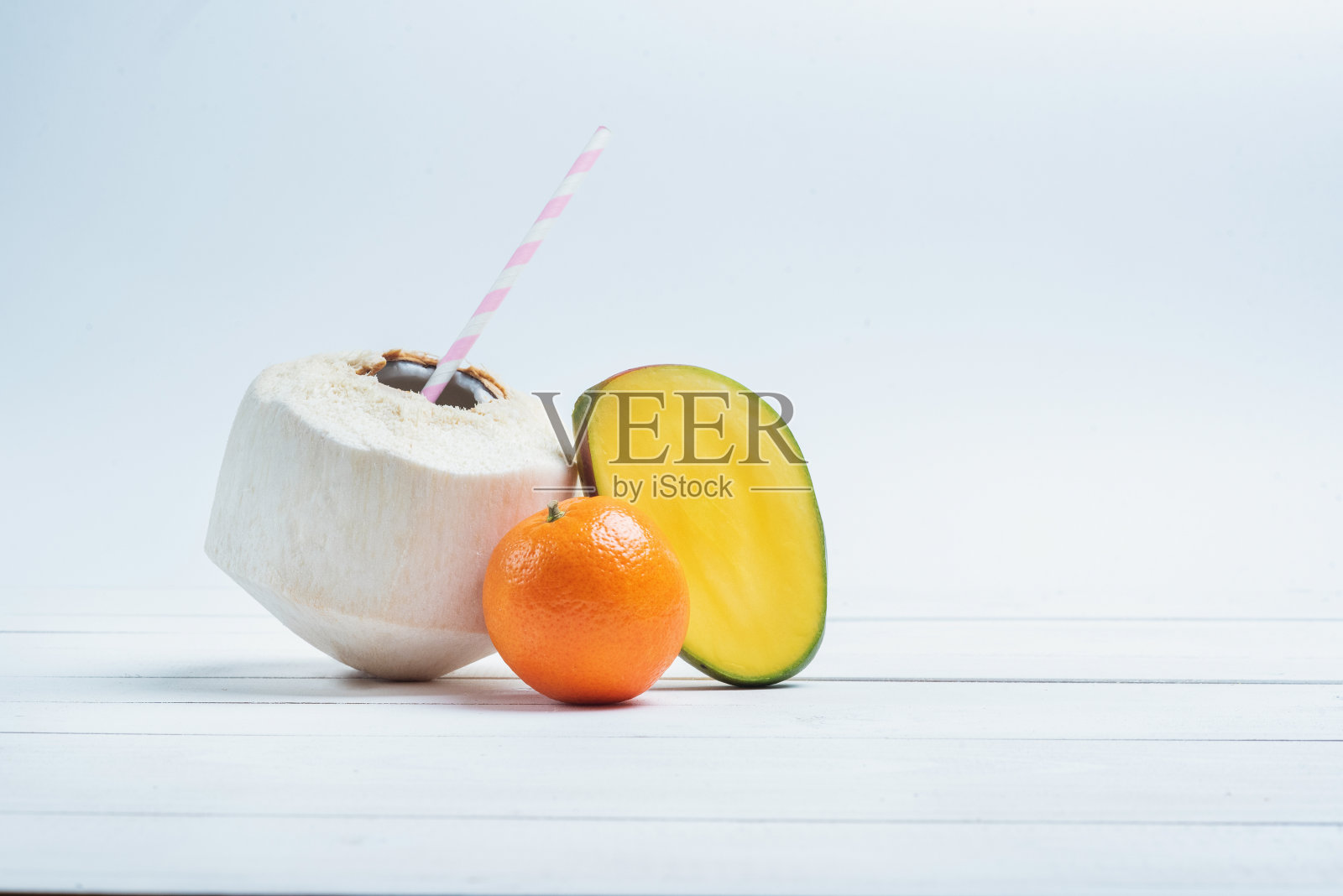 用吸管喝椰子，一半芒果和桔子。照片摄影图片