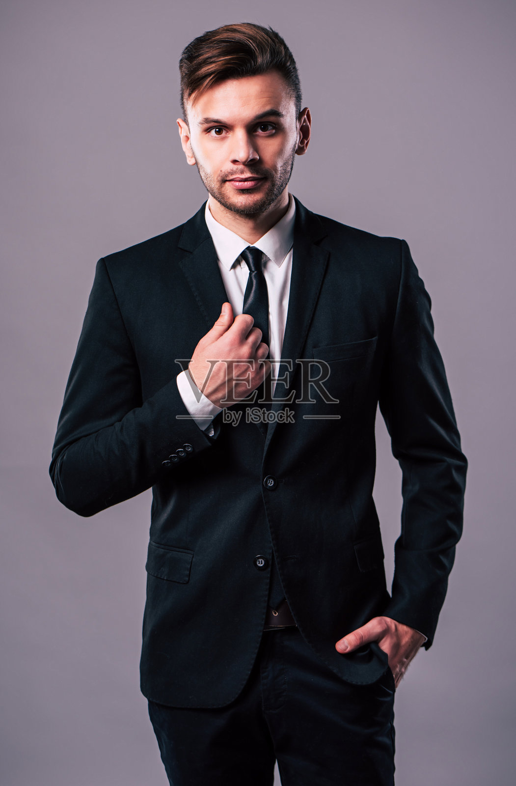 时尚优雅和自信的年轻商人是在灰色的背景照片摄影图片