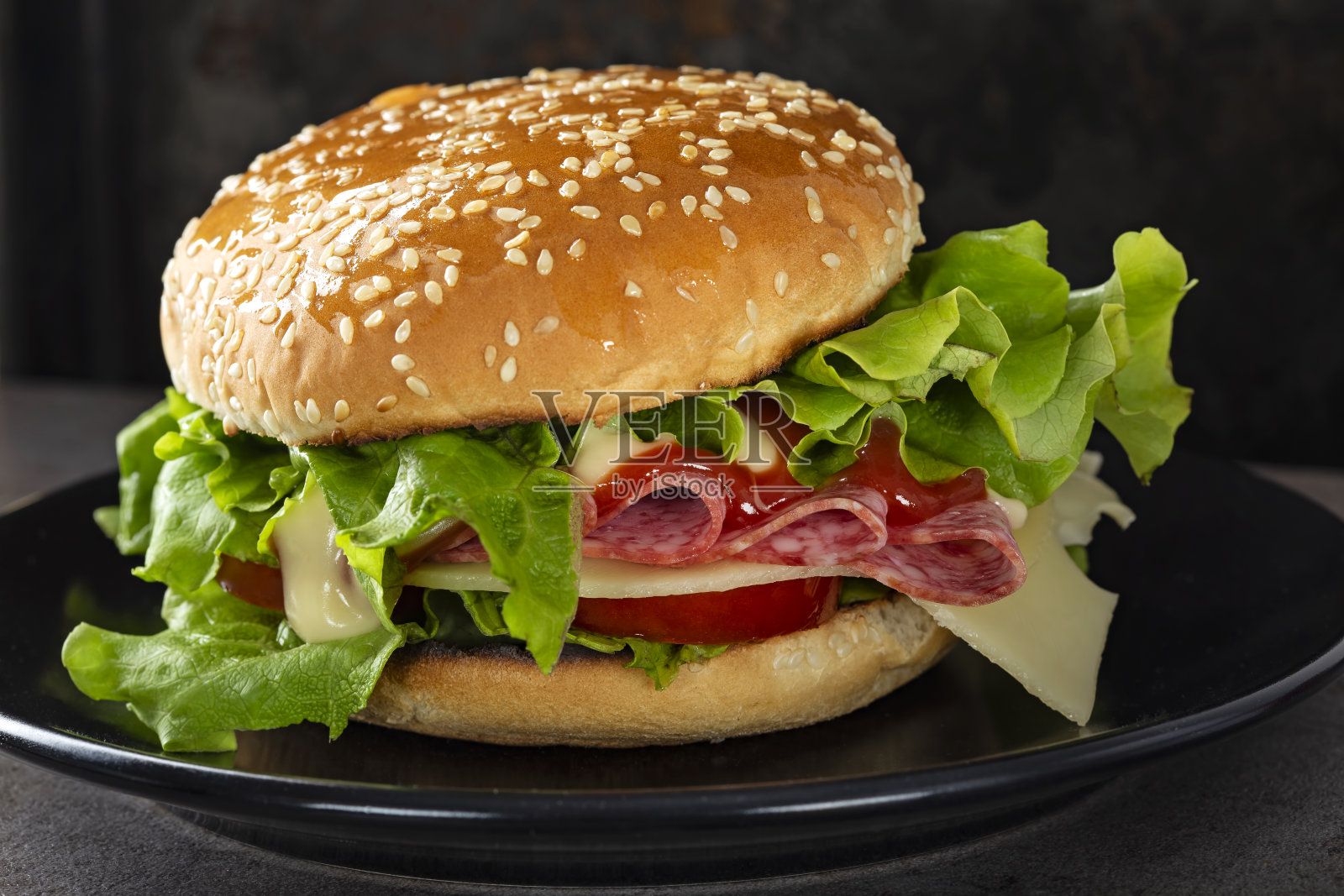 一个有意大利腊肠、奶酪、西红柿和酱汁的三明治照片摄影图片