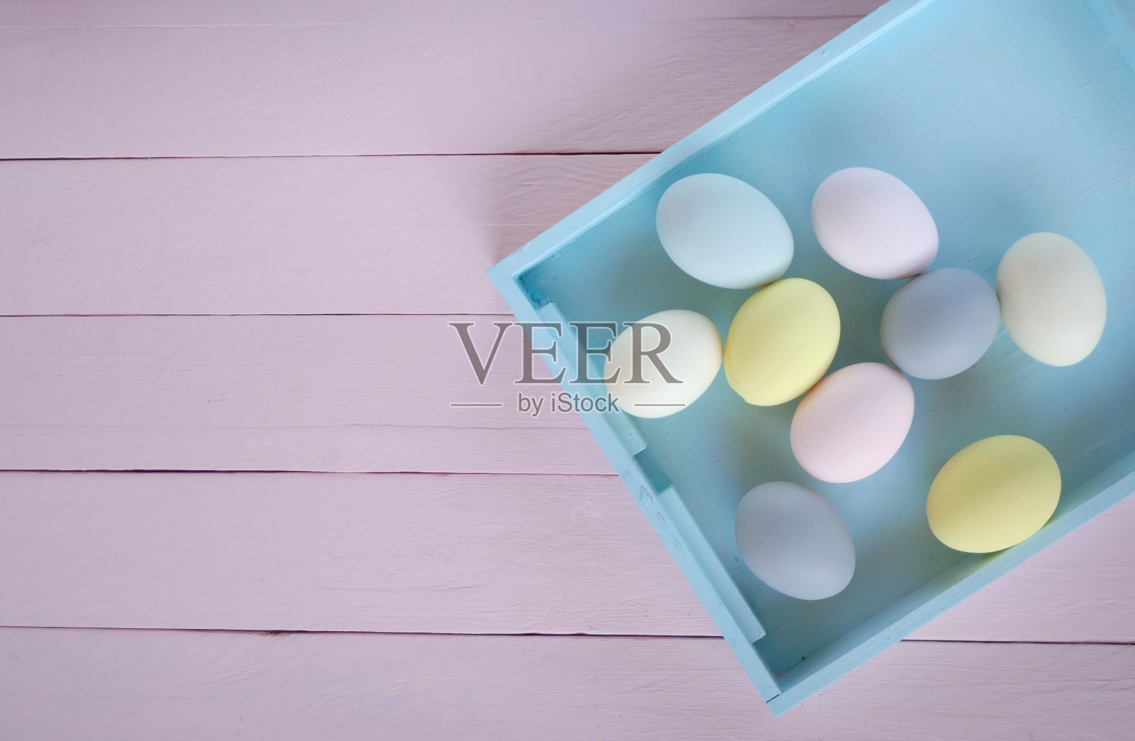 复活节的概念。色彩柔和的复活节彩蛋在一个淡蓝色托盘上，粉红色的木板背景。俯视图，复制空间。复活节假期。春天的季节照片摄影图片