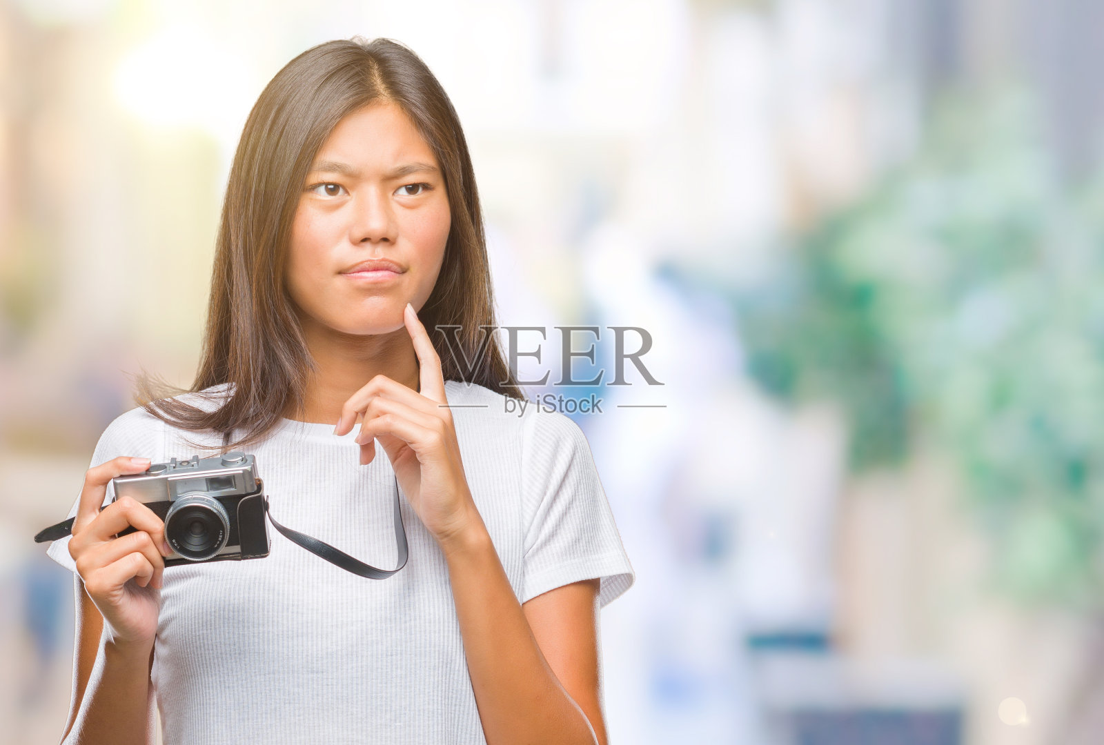 年轻的亚洲女子拿着复古相机在孤立的背景下严肃地面对问题思考，非常困惑的想法照片摄影图片