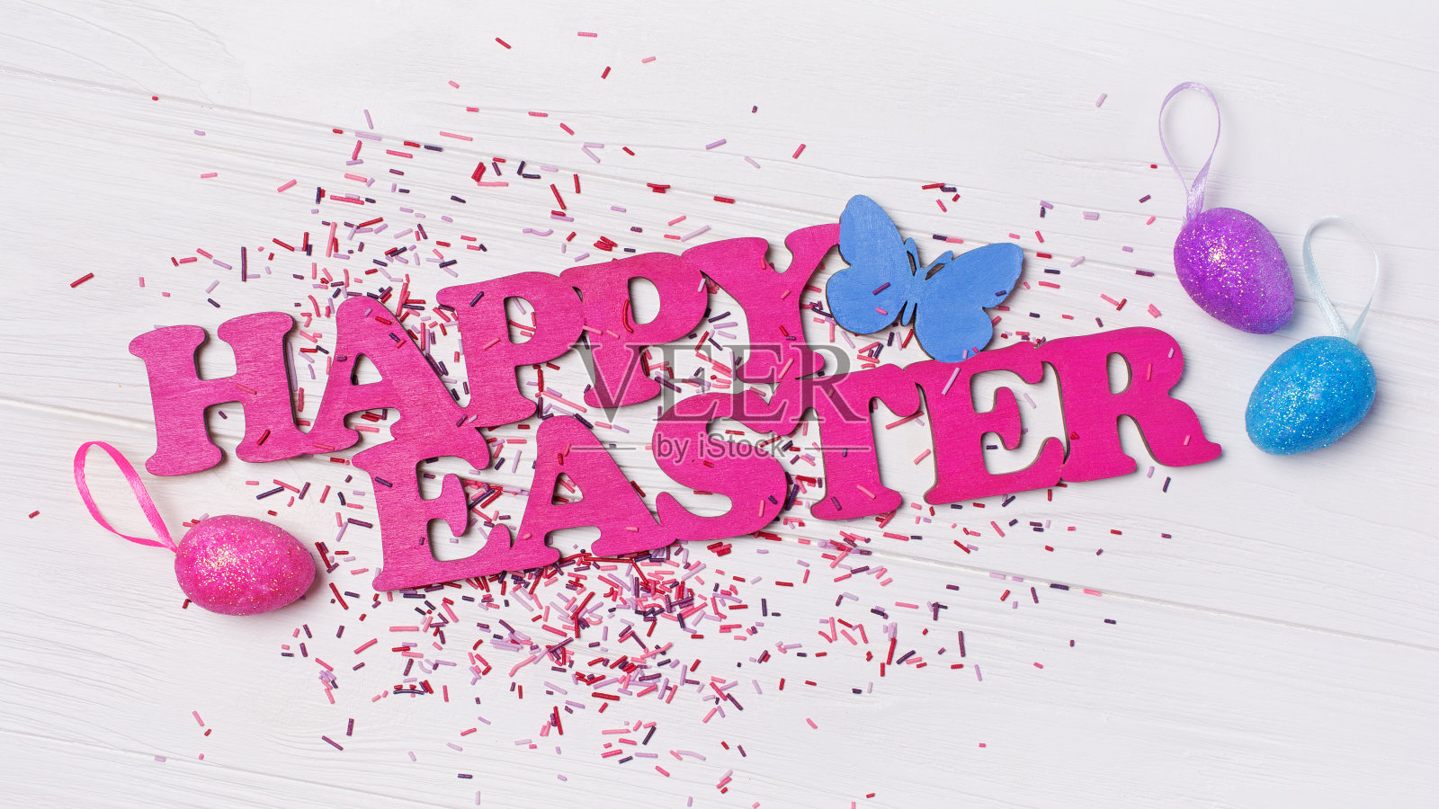 顶视图上的粉色文字快乐复活节和鲜艳的彩色糖屑或五彩纸屑照片摄影图片