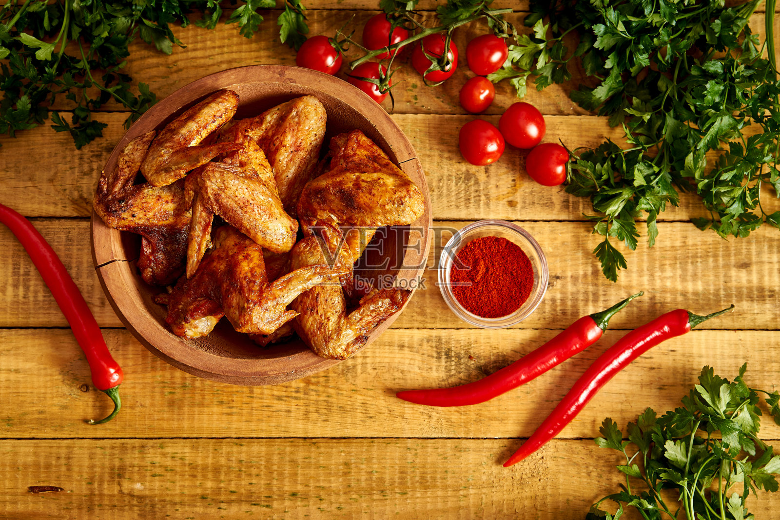 美味的烤鸡翅在木碗，香料和蔬菜在木桌上。照片摄影图片