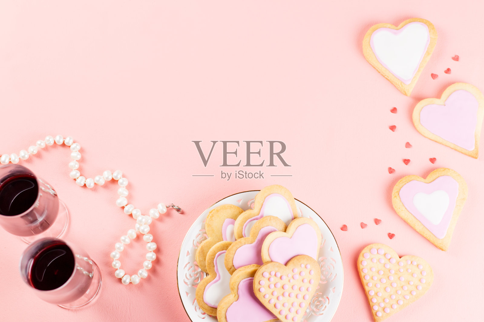 情人节贺卡心形饼干，酒杯和葡萄酒在柔和的粉红色背景。照片摄影图片
