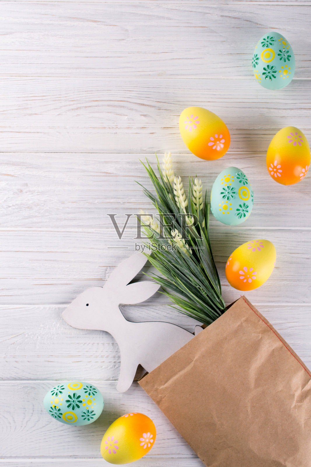 复活节构图用牛皮纸包装，五彩缤纷的复活节彩蛋，装饰木兔子和鲜花。平铺，俯视图，拷贝空间照片摄影图片