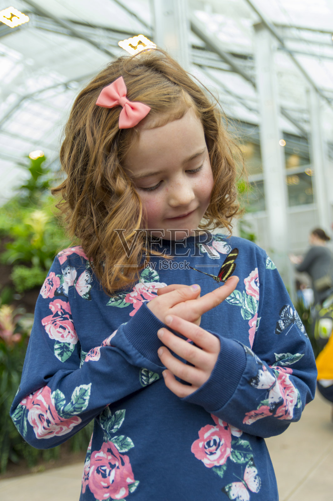 年轻女孩欣赏一只栖息在她手指上的蝴蝶照片摄影图片