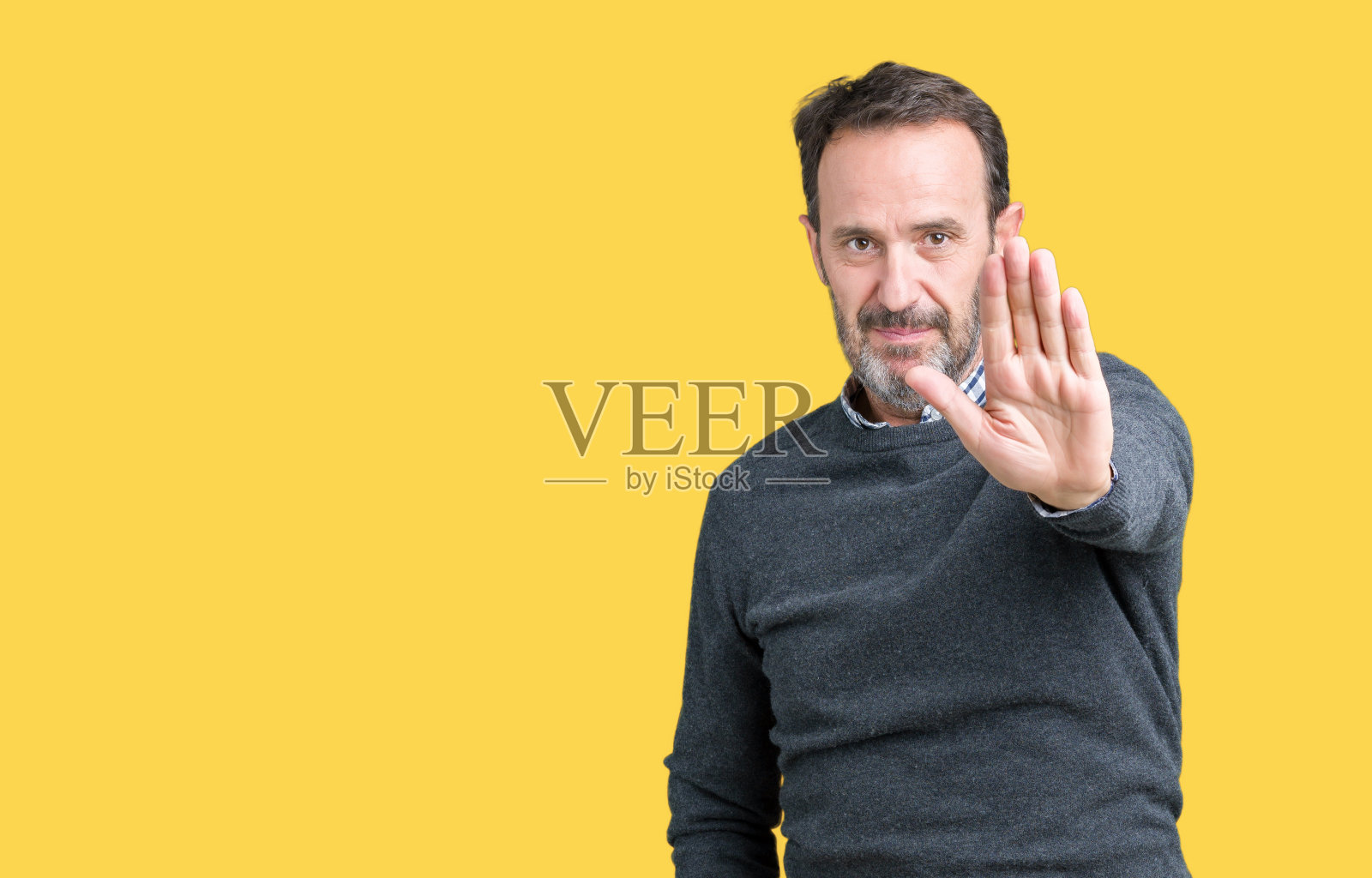 英俊的中年老人穿着一件毛衣过孤立的背景做停止唱歌与手掌。警告表情与否定和严肃的手势在脸上。照片摄影图片