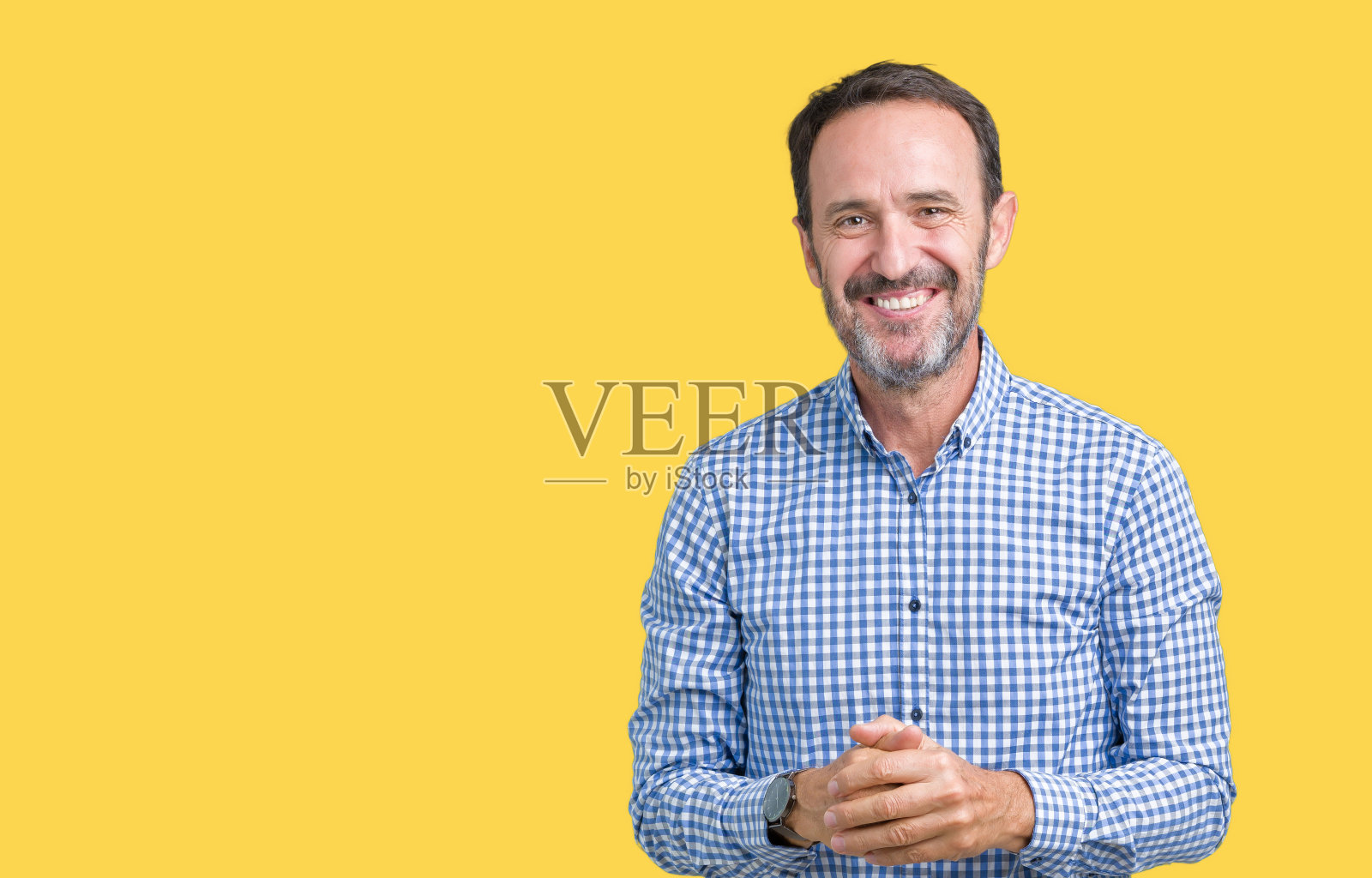 英俊的中年优雅的资深男子在孤立的背景双手交叉，手指交叉微笑轻松和愉快。成功和乐观照片摄影图片