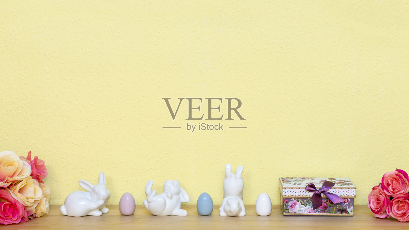 两束玫瑰花束三只白色兔配三个复活节彩蛋和一份礼物照片摄影图片