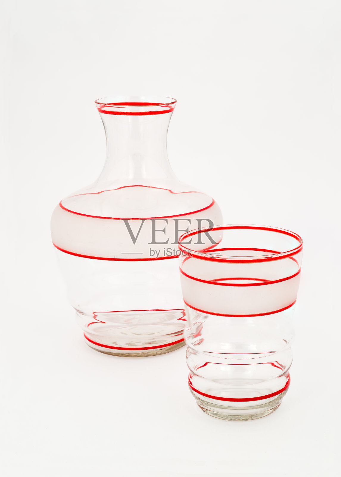 带有红色条纹的清水水壶和玻璃杯。照片摄影图片