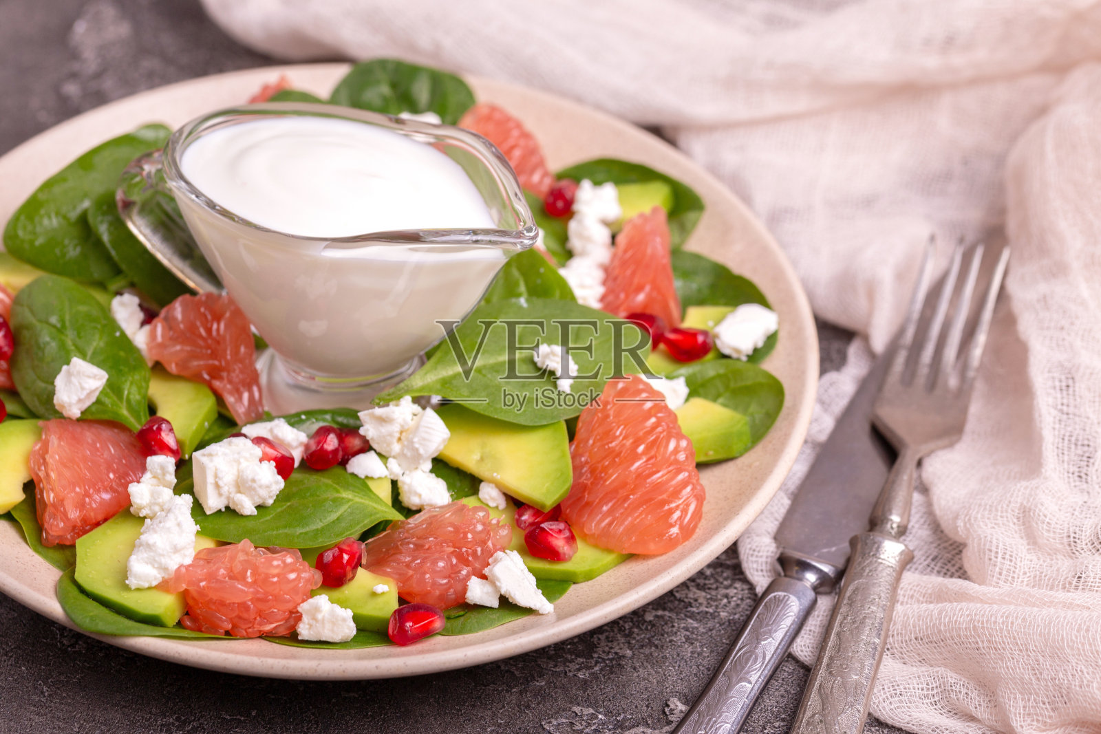 美味的葡萄柚沙拉，菠菜，羊乳酪，鳄梨和石榴与酸奶油盘子照片摄影图片