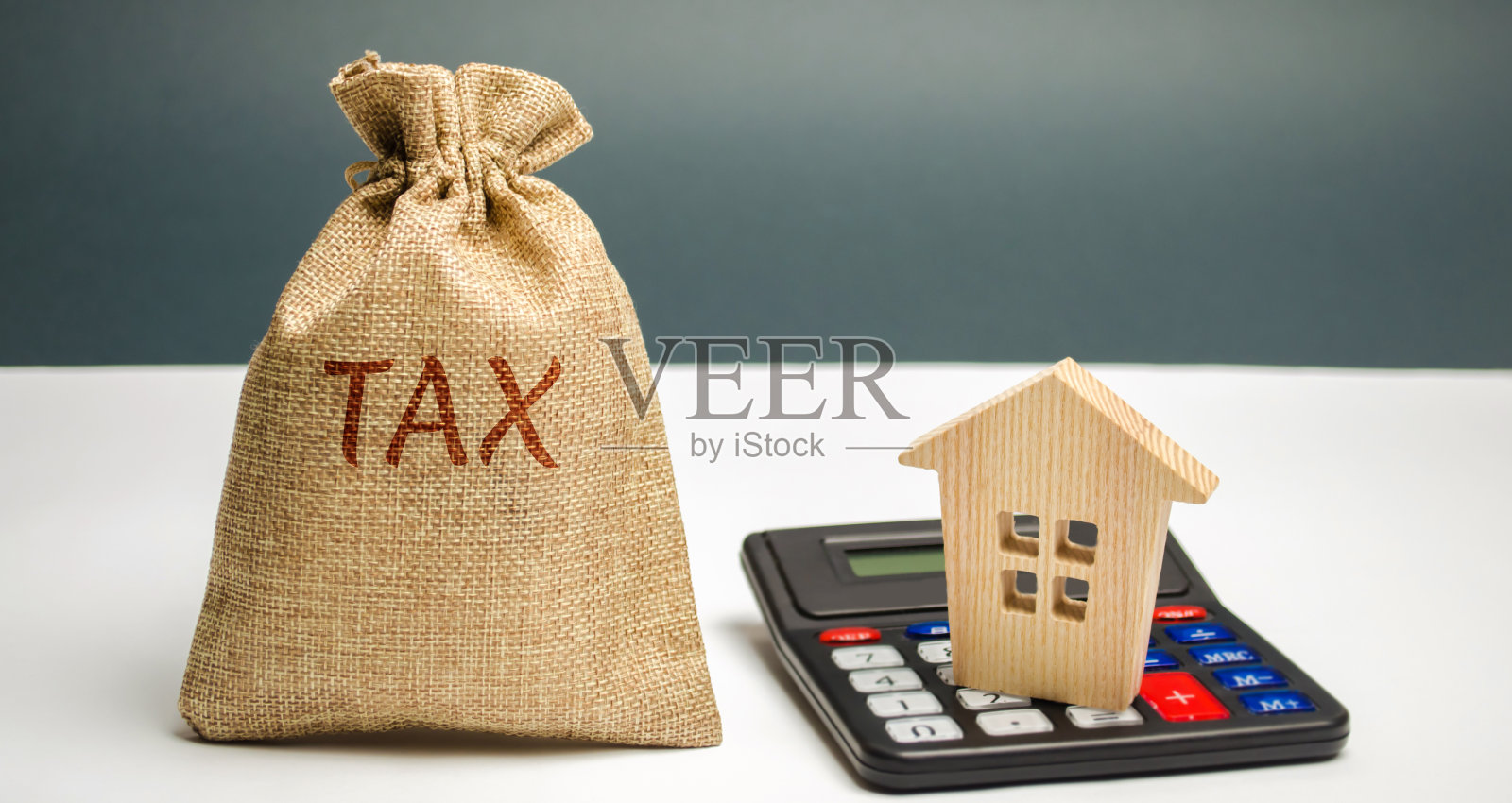 一个写着“税”的袋子和一个带房子的计算器。房地产税，支付。点球,欠款。纳税人财产登记册。守法，偷工减料。法院的法律。奢侈税照片摄影图片