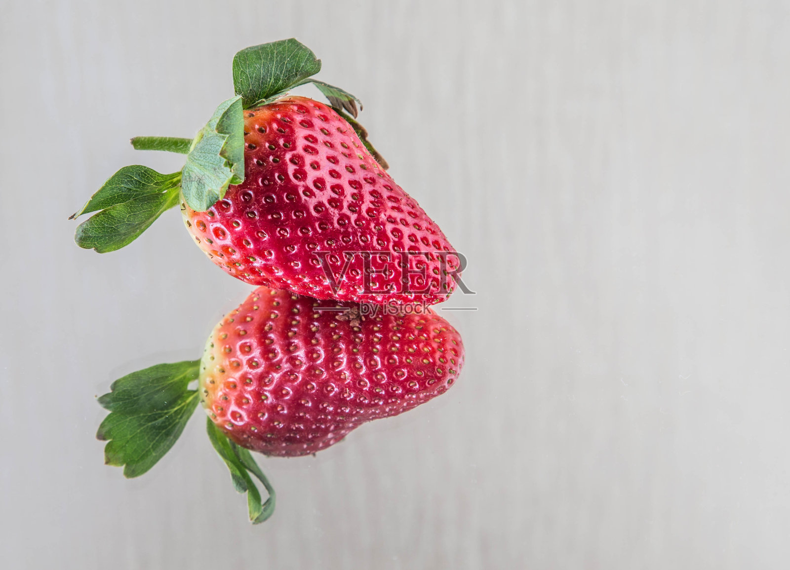 单一草莓反射在镜子上照片摄影图片