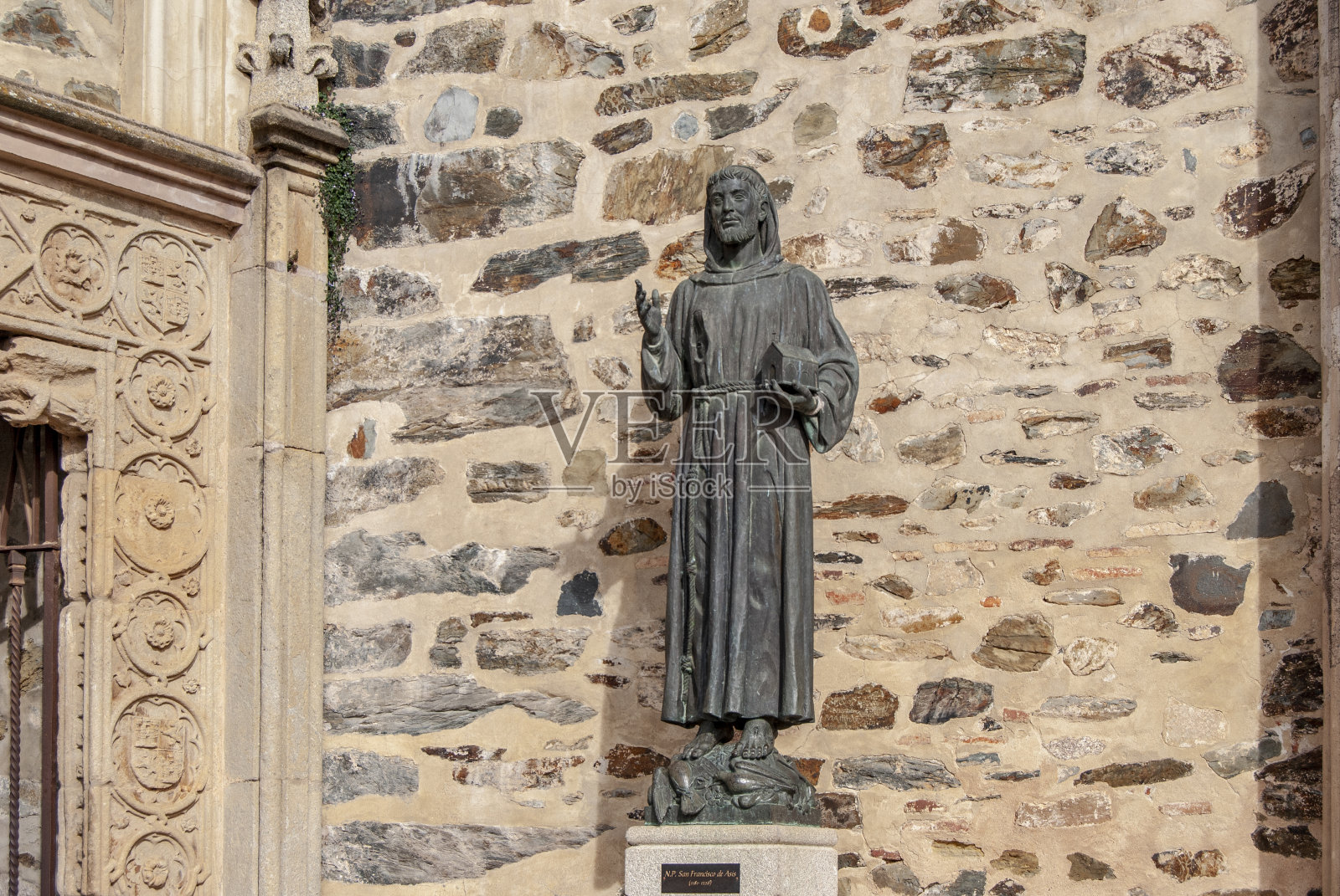 西班牙卡塞雷斯省瓜达卢佩修道院入口的阿西西方济各铜像照片摄影图片