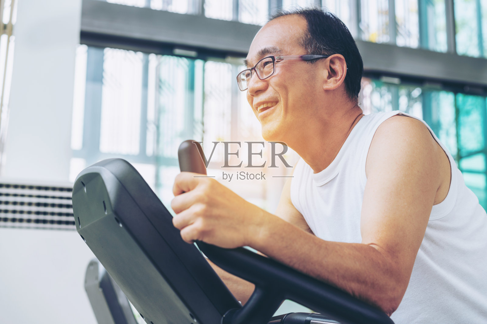 老人在健身中心的跑步机上锻炼照片摄影图片