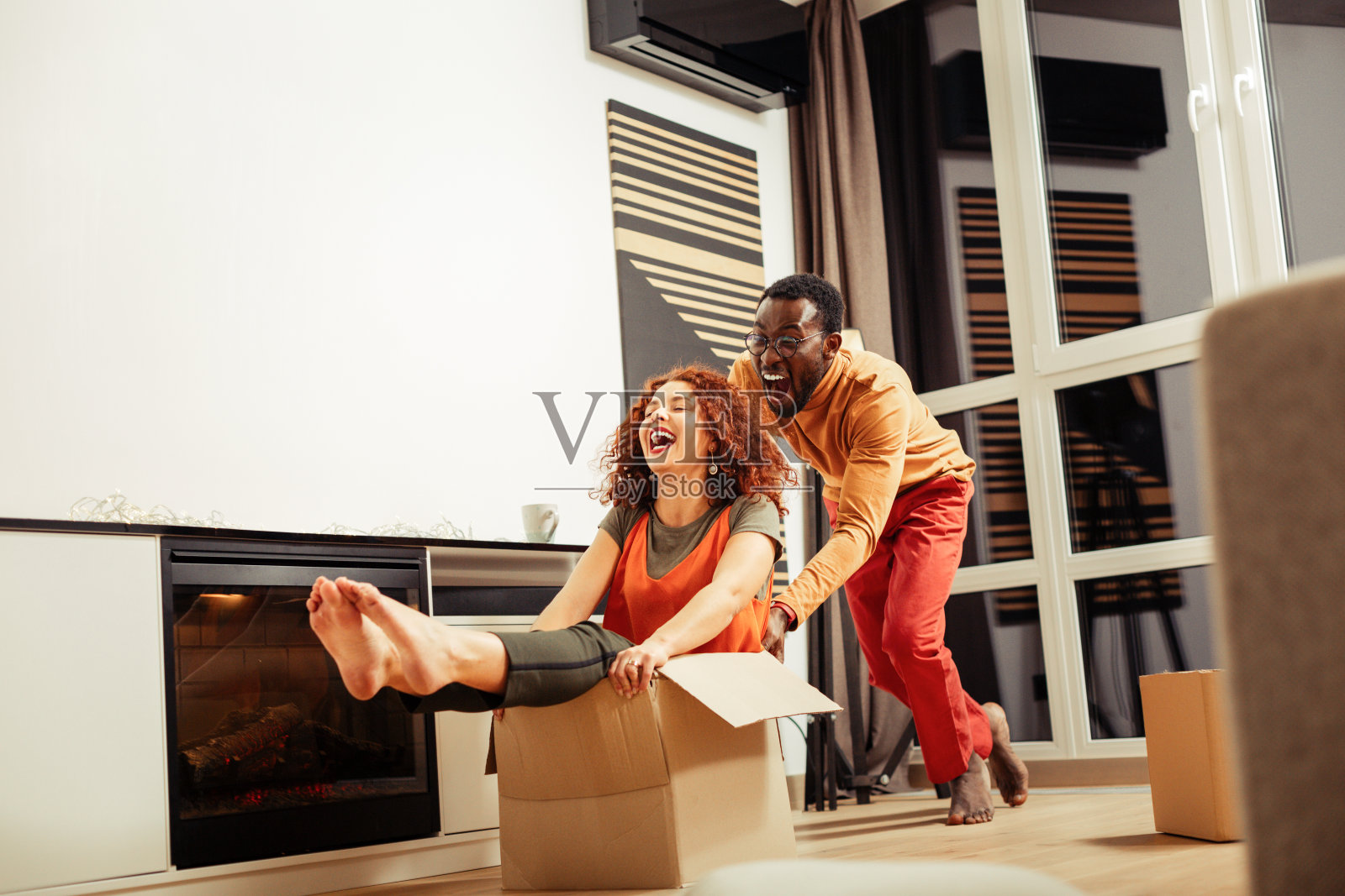 欢笑的非裔美国丈夫指导妻子搬箱子照片摄影图片
