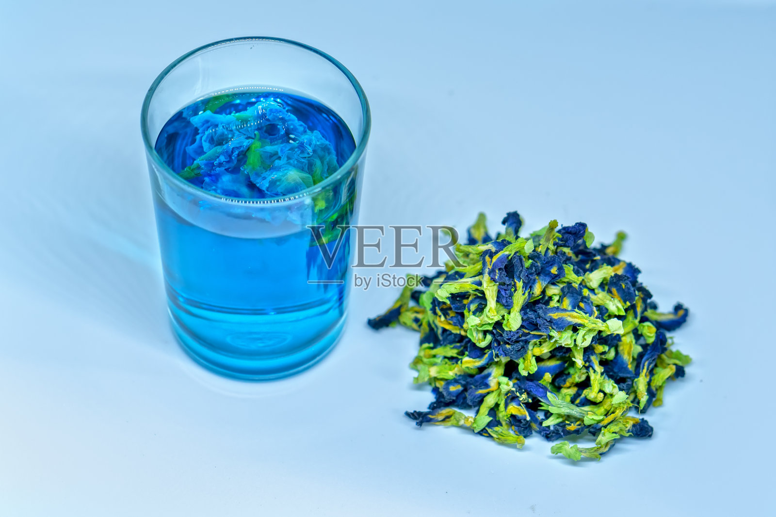 蝴蝶豌豆花干茶，并将其倒入一个透明的杯子中照片摄影图片
