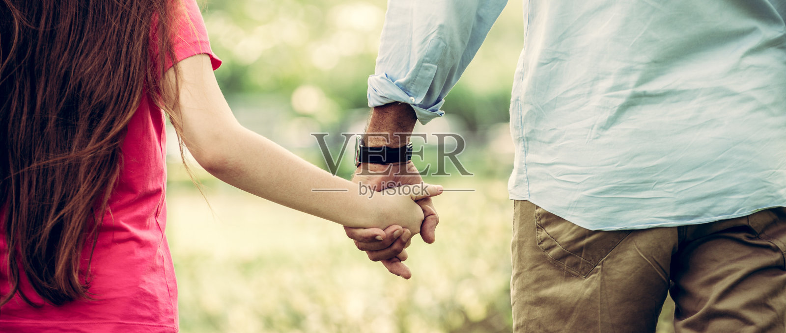 父亲和女儿手牵着手在公园里。照片摄影图片