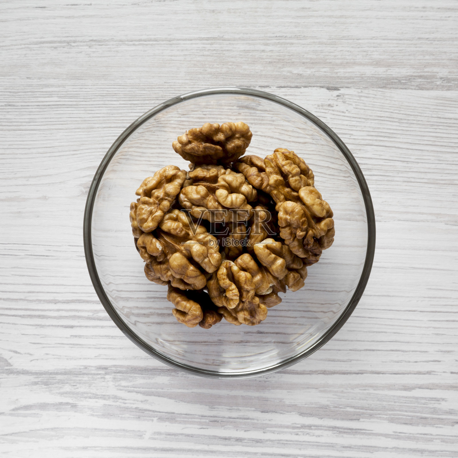 核桃在玻璃碗上白色木质表面，俯视。特写镜头。平躺，从上面俯视。照片摄影图片