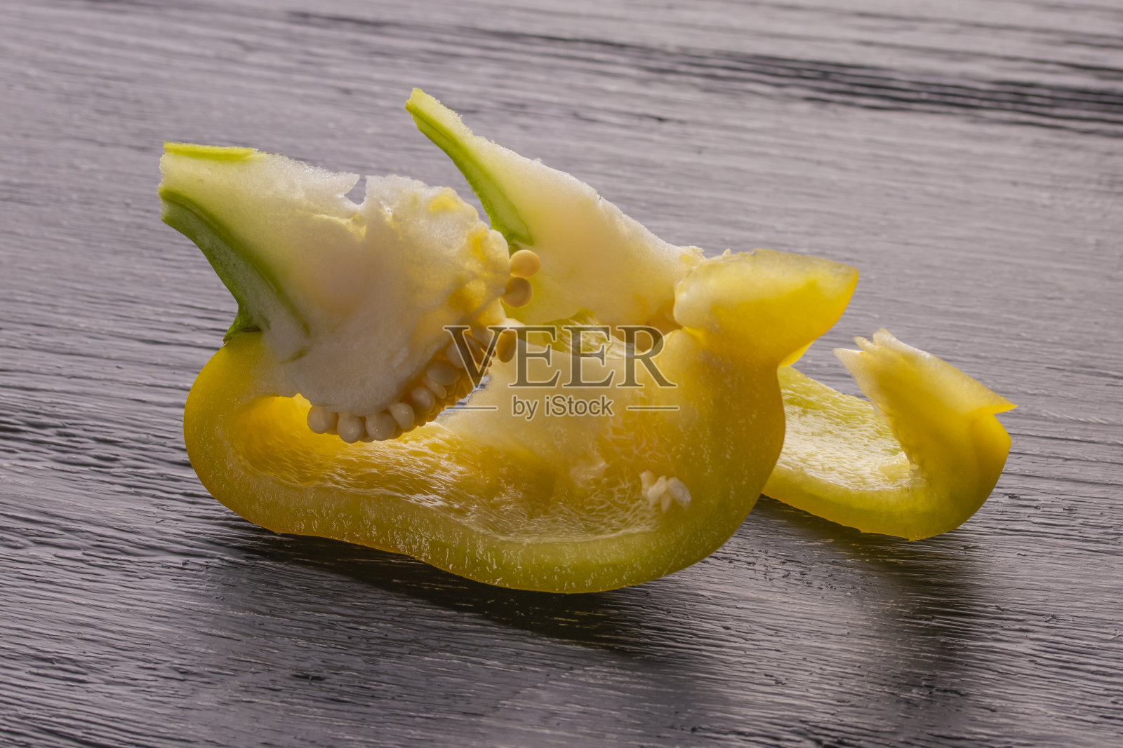 黄色的甜椒片放在黑色的木桌下面照片摄影图片