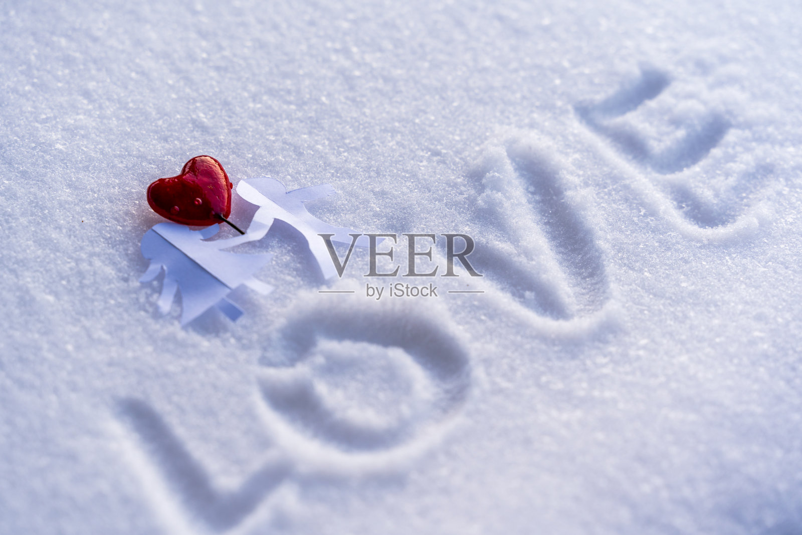 孤立的折纸男孩和女孩手牵手与他们之间的红心在白雪的背景与文字空间-爱，幸福和快乐的概念在情人节照片摄影图片