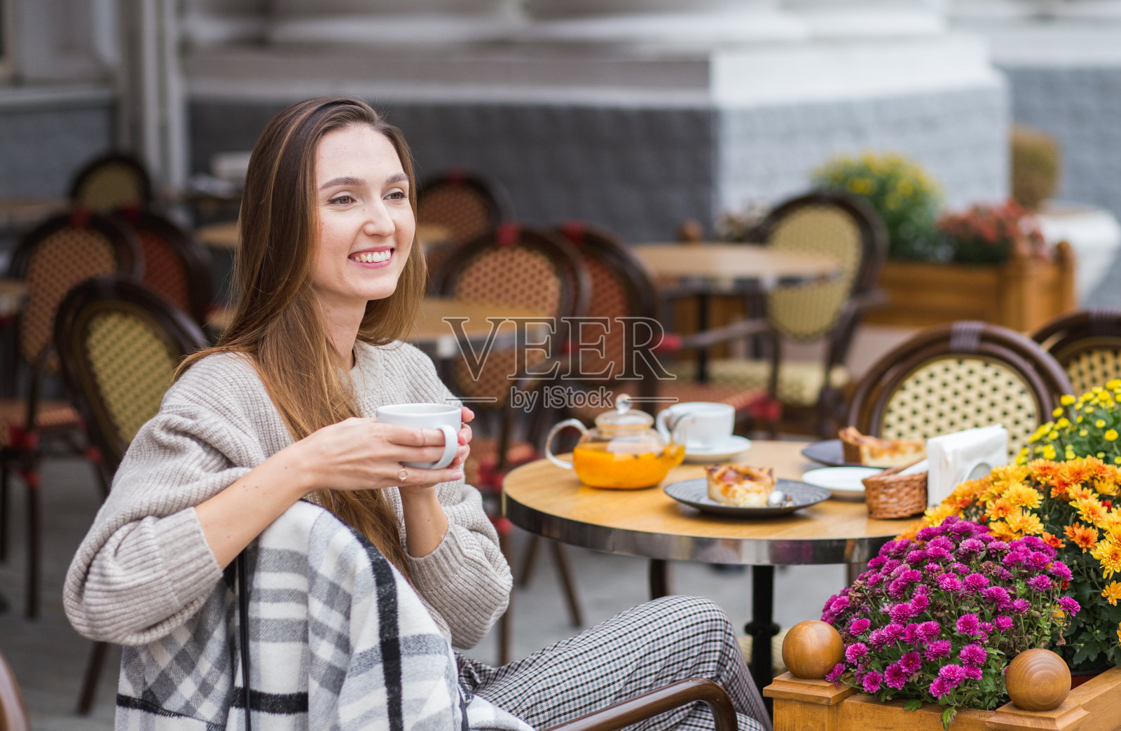 年轻时尚的女人正坐在咖啡厅的露台上享用法式早餐，咖啡和蛋糕照片摄影图片