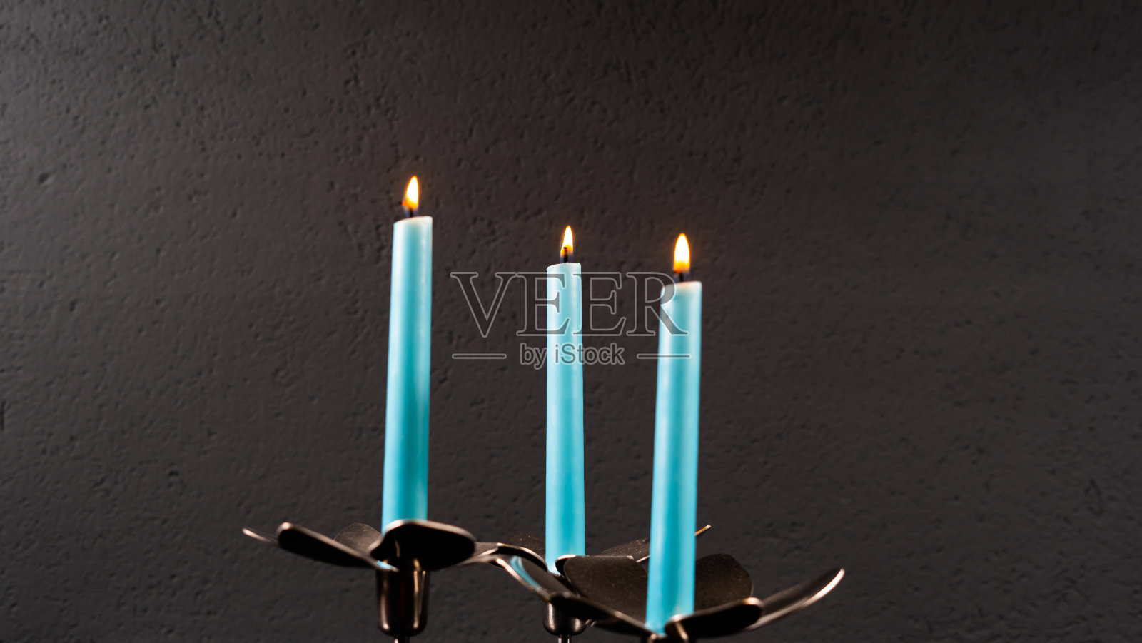 蓝色的蜡烛孤立在黑暗的背景上，照片摄影图片