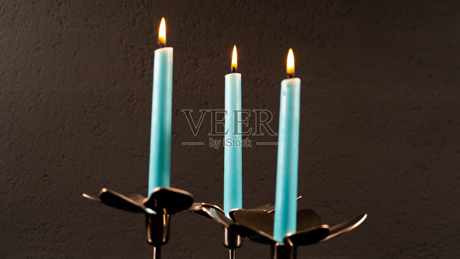 蓝色的蜡烛孤立在黑暗的背景上，照片摄影图片