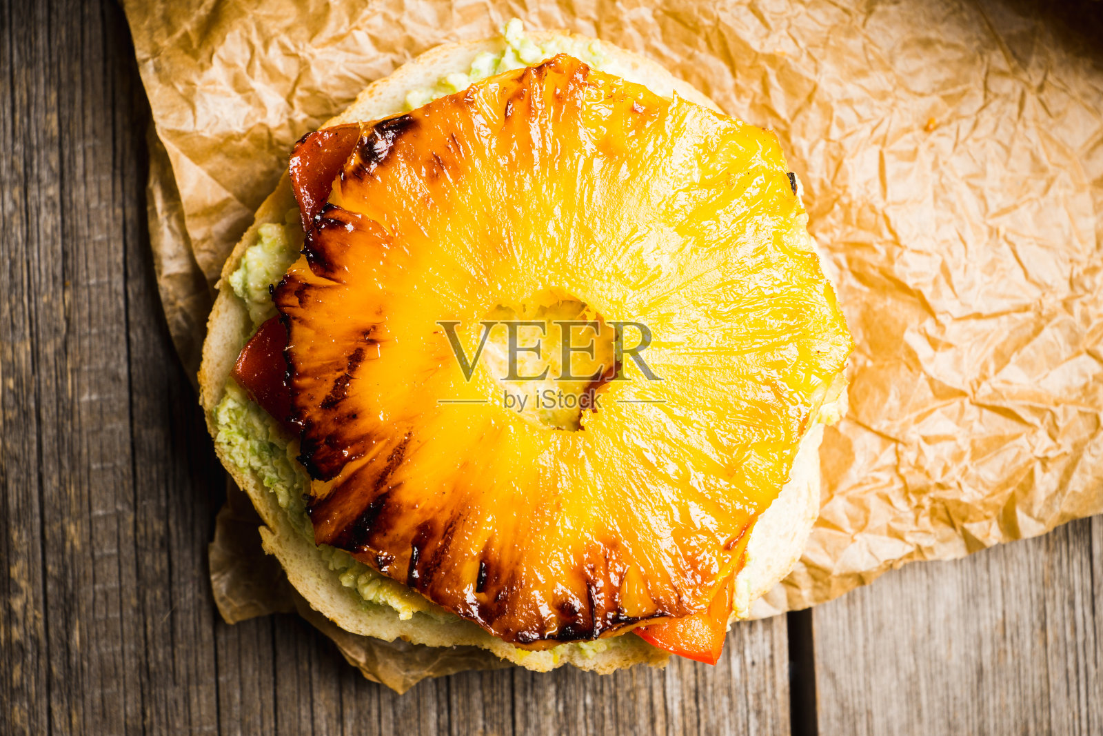 夏威夷素食汉堡配烤菠萝，鳄梨色拉酱和烤甜椒。有选择性的重点。景深浅。照片摄影图片