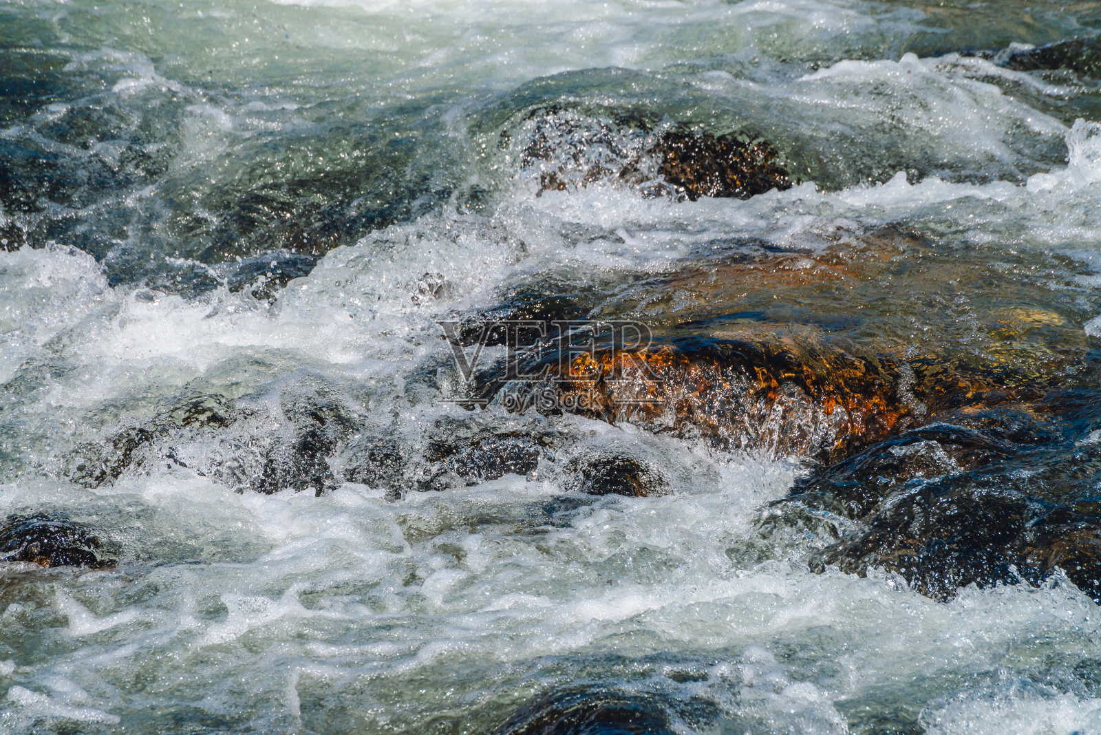 山溪中的巨石特写。湍急的河流与复制空间。泡沫水流。在潮湿的石头附近快速流动。背景清水海浪。自然纹理的小溪闪闪发光照片摄影图片