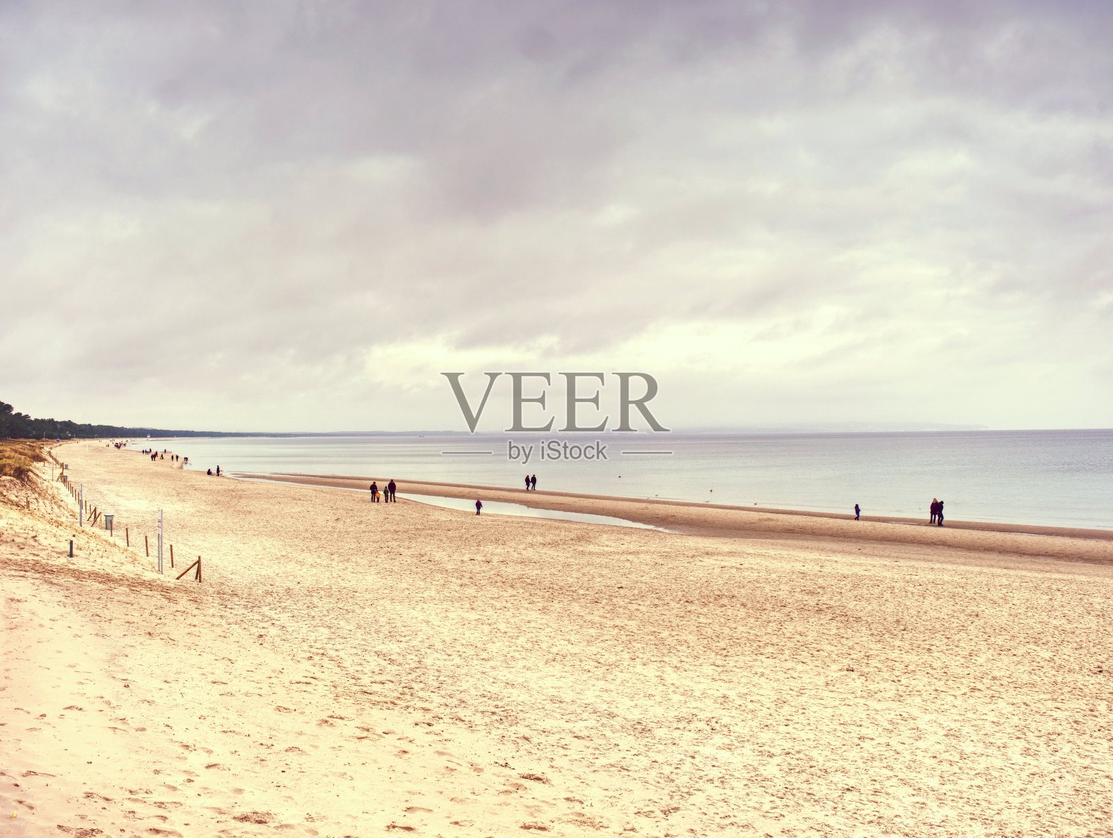 游客走在沙滩上，从木桥上欣赏风景照片摄影图片