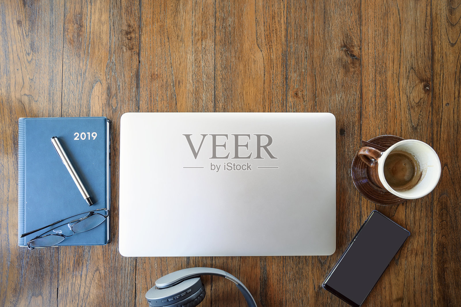 俯视图笔记本电脑，智能手机，耳机，书和一杯咖啡在木桌上。照片摄影图片