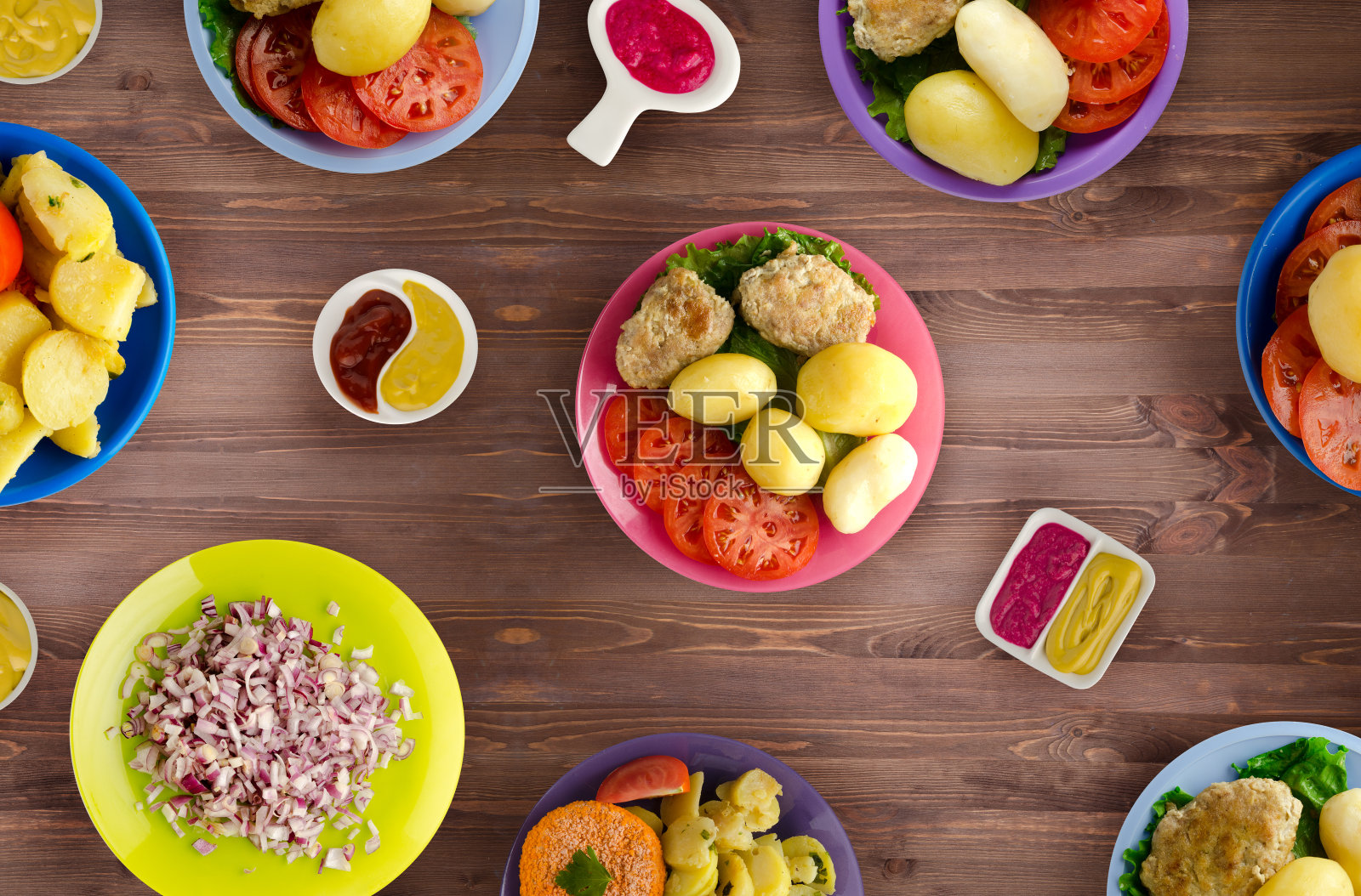 美味的调味炸猪排用辣味腌料烹制，配以煮土豆、沙拉和酱汁。木桌上的一盘肉片照片摄影图片