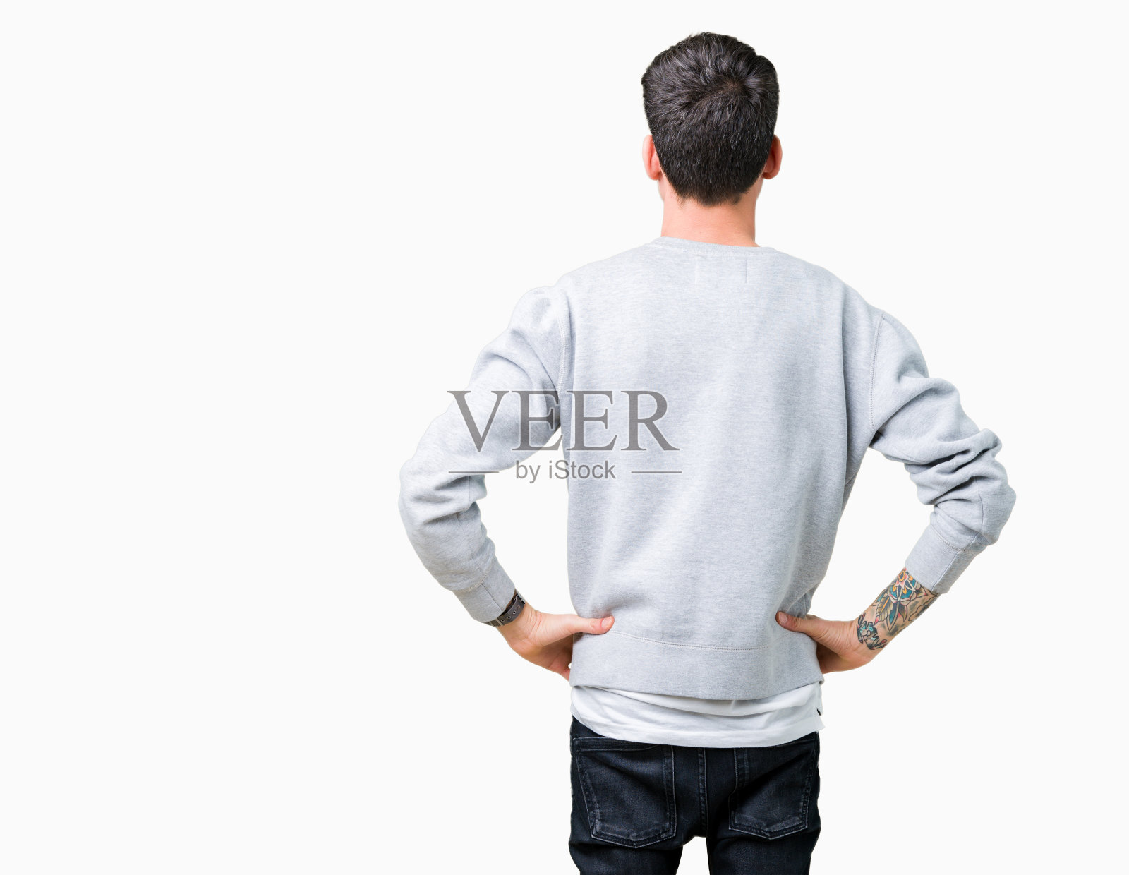 年轻英俊的男子穿运动衫在孤立的背景站向后看远离与手臂上的身体照片摄影图片