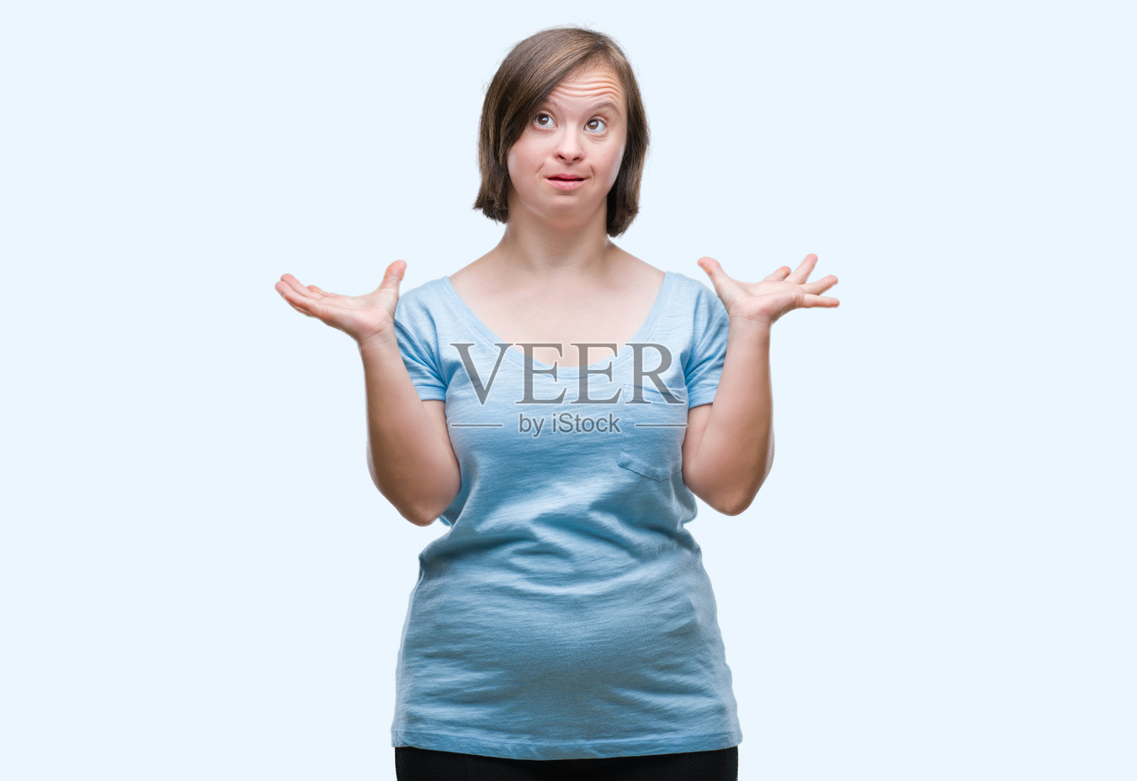 患有唐氏综合症的年轻女子在孤立的背景下庆祝成功，张开双臂，睁大眼睛尖叫，欣喜若狂照片摄影图片