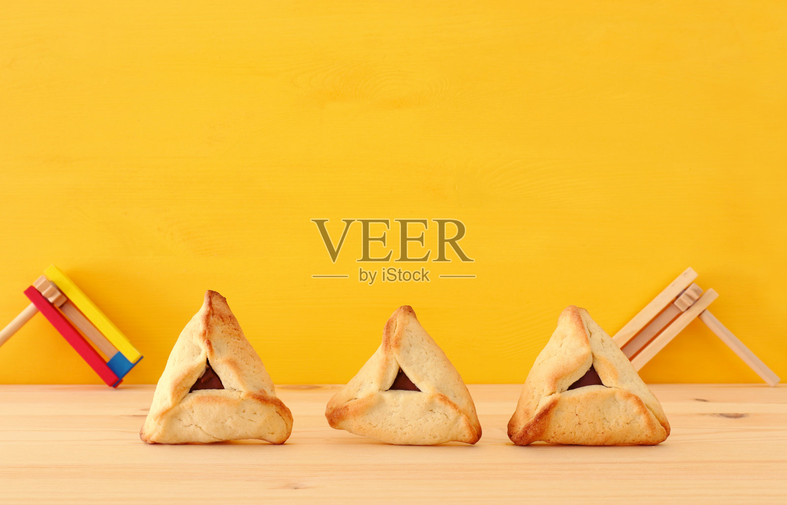 普林节庆祝概念(犹太狂欢节节日)。传统的日式烤饼放在木桌和黄色背景上。照片摄影图片