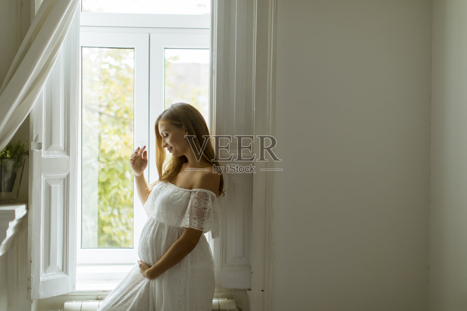 站在窗边的年轻孕妇照片摄影图片